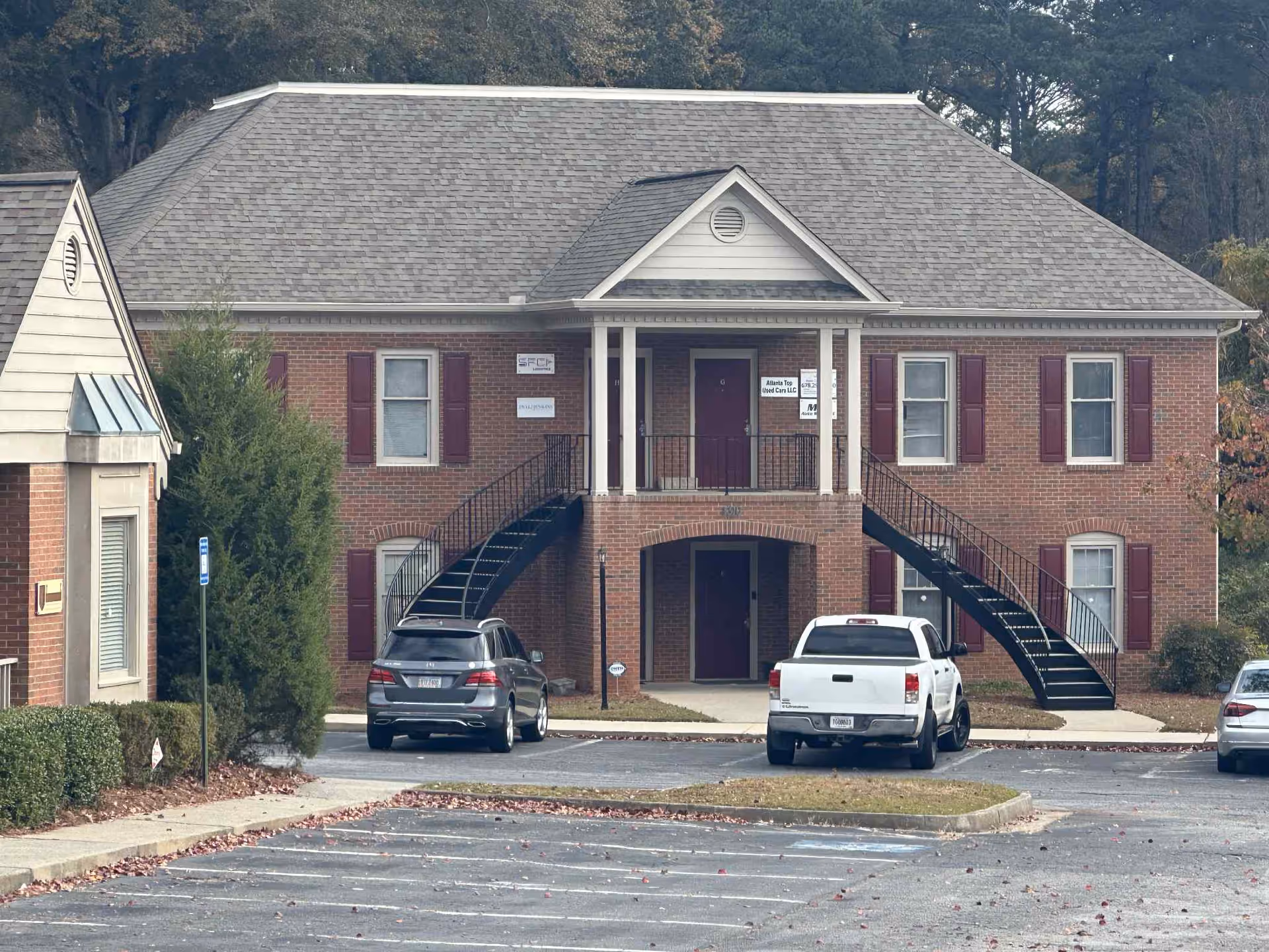 Brick senior living facility with front entrance, two staircases, and parked cars.