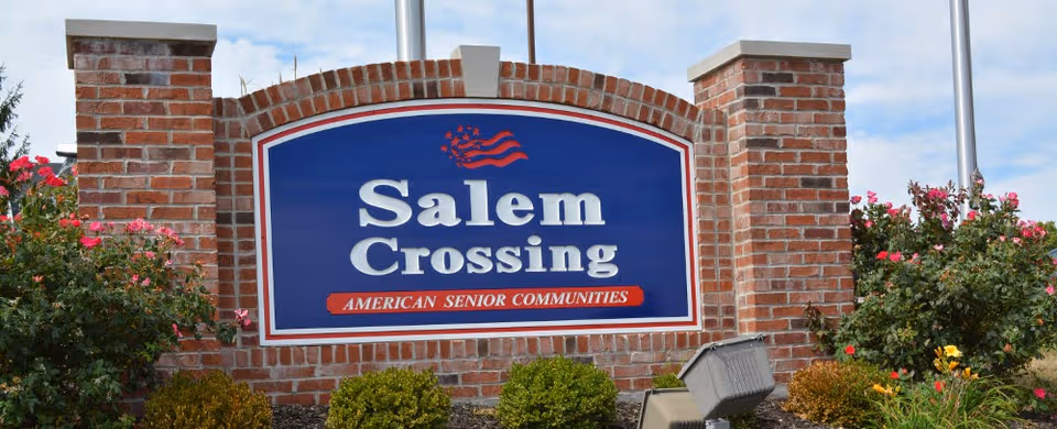 Brick entrance with a large blue Salem Crossing sign and landscaping.