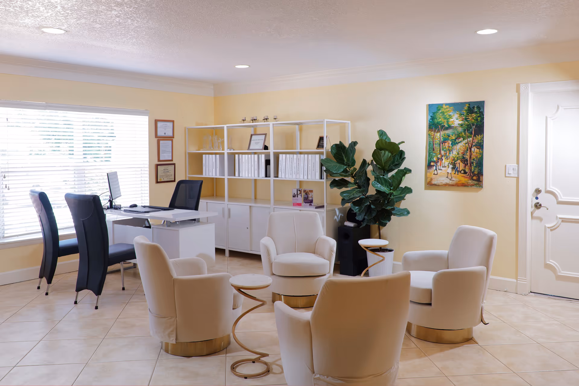 Bright, airy waiting lounge in a senior facility with white chairs, desk, shelves, and plants.