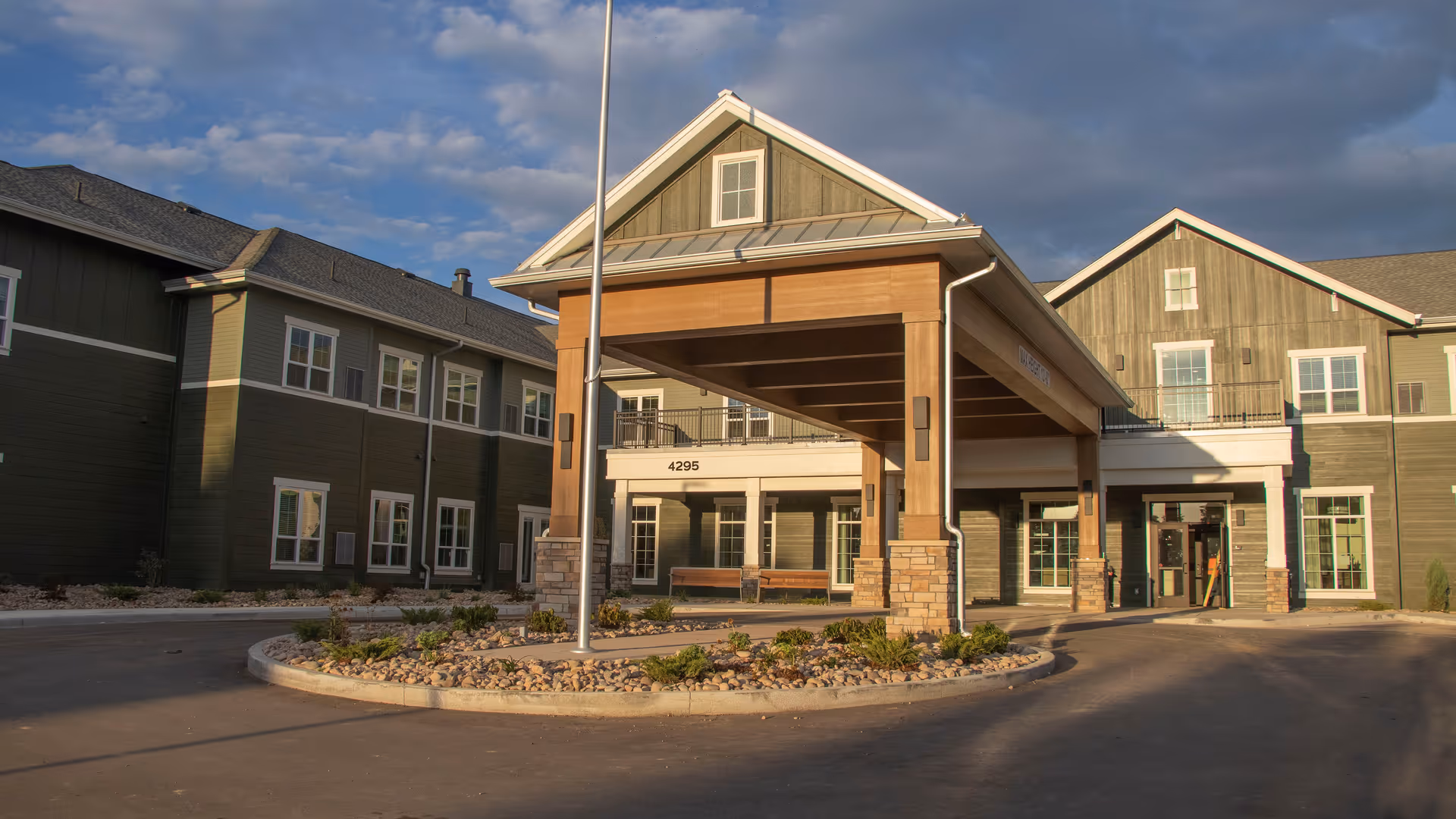 Front exterior of Stoneridge at Centerra with a covered entrance and green siding.