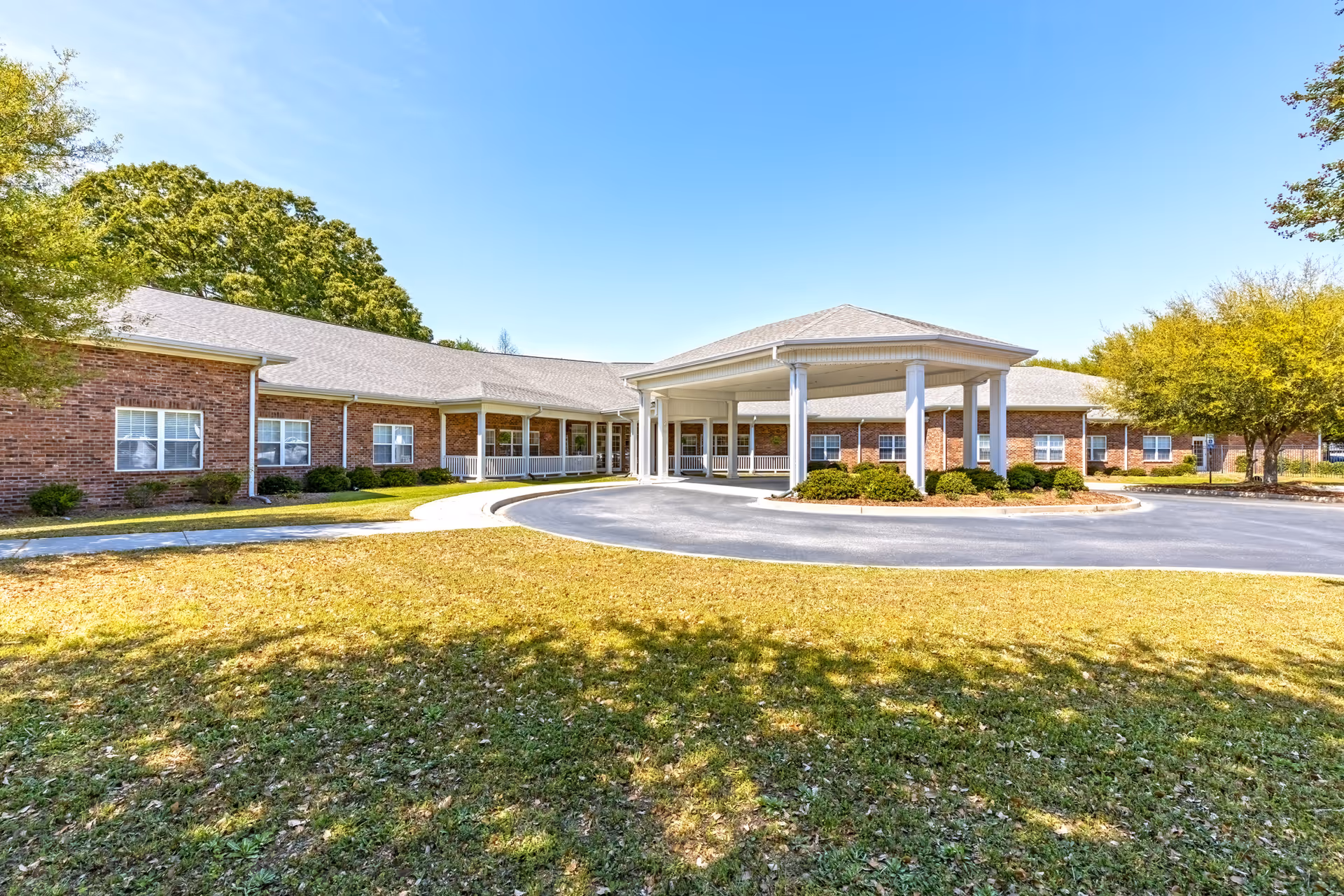 Brick senior living facility The Gardens at Sumter with a covered entrance and circular driveway.