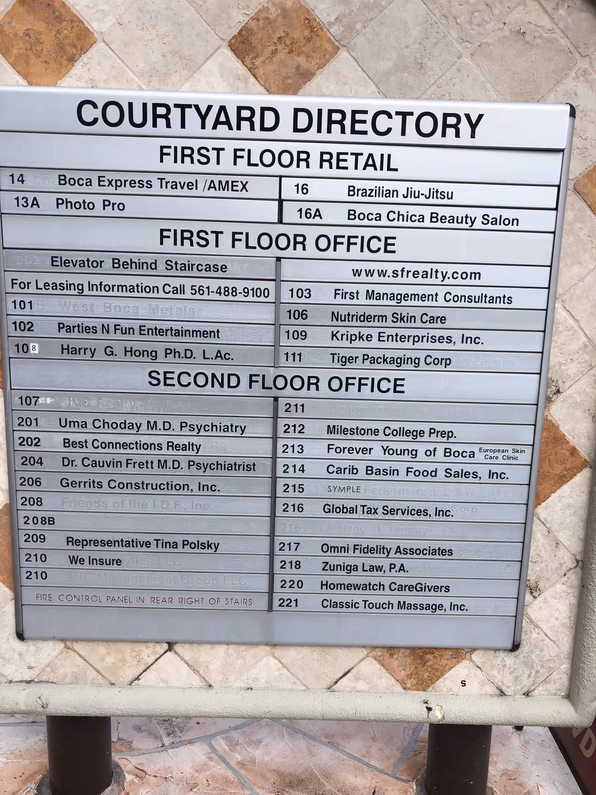 Exterior courtyard directory board listing offices and tenants, including Homewatch CareGivers, Boca Raton.
