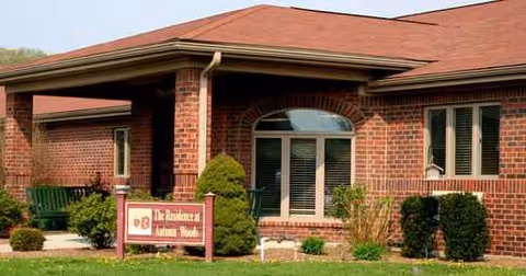 Red brick senior living facility exterior with entrance canopy and landscaped shrubs.