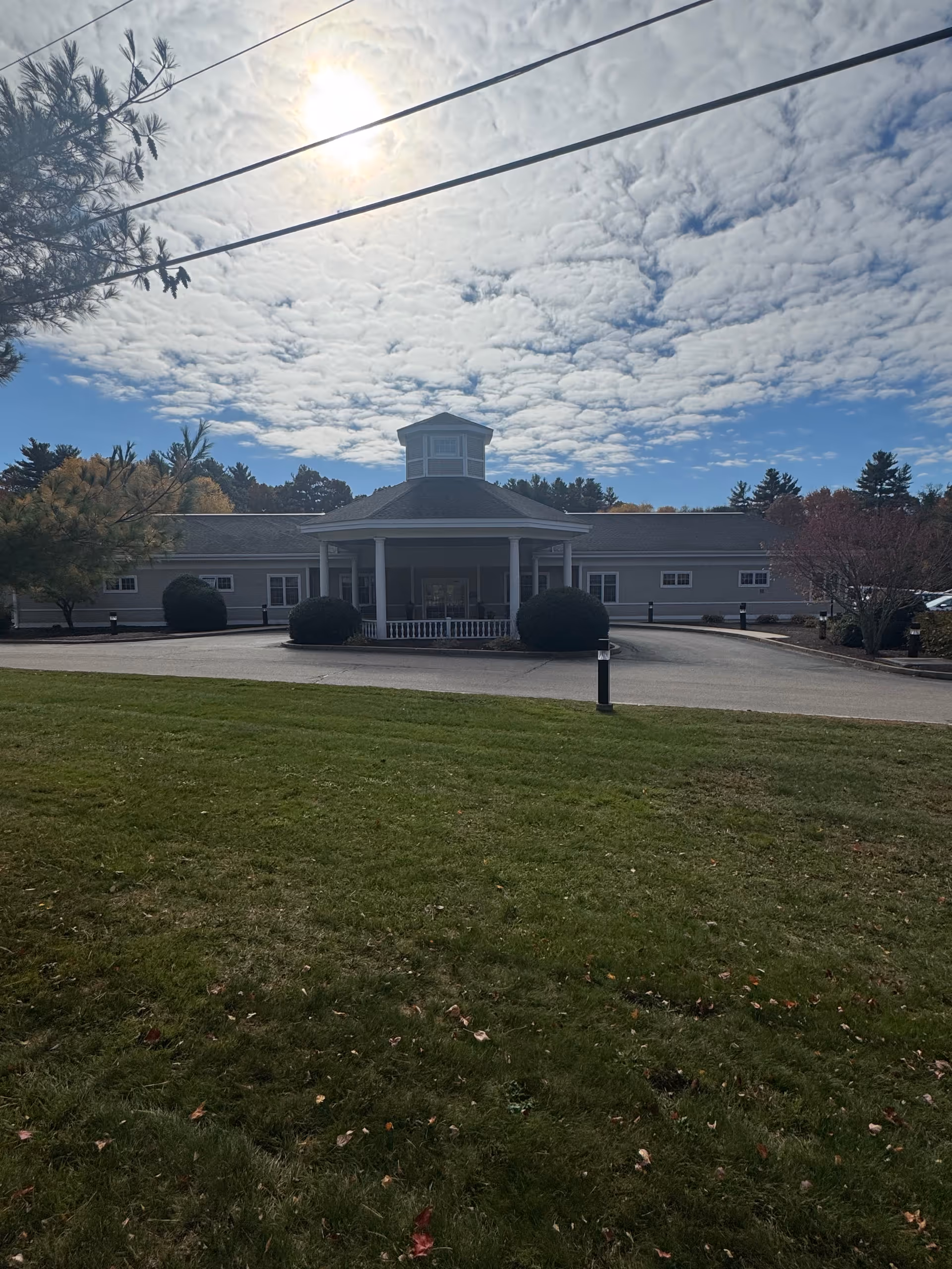 Front view of Nemasket Healthcare Center showing its entrance, driveway, lawn, and sunny sky.