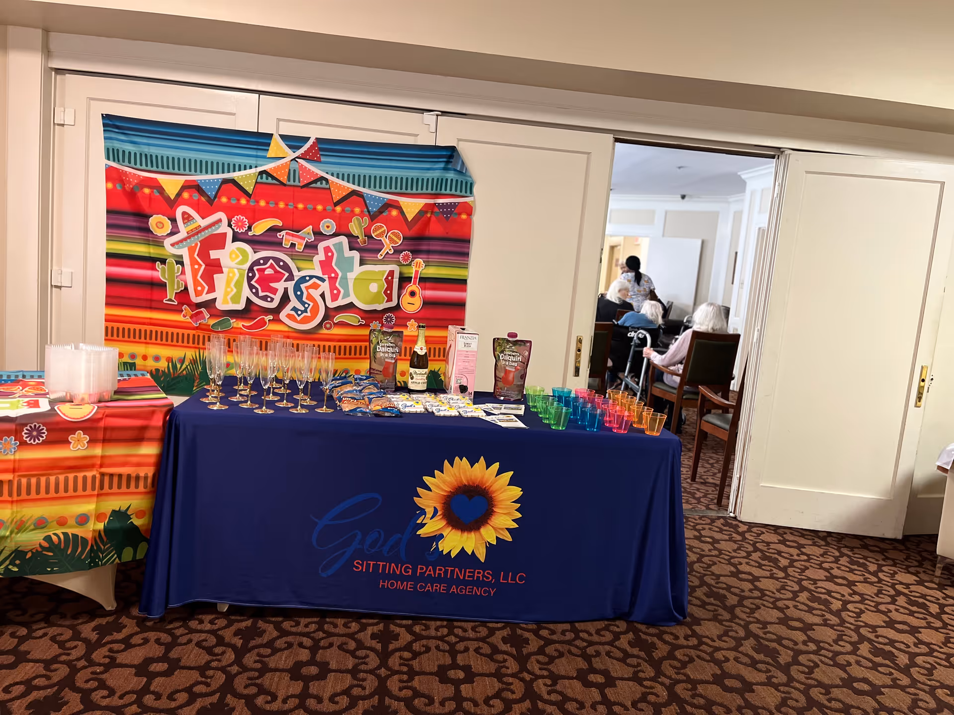 Fiesta-themed event setup in a senior living facility with drinks and a colorful banner.