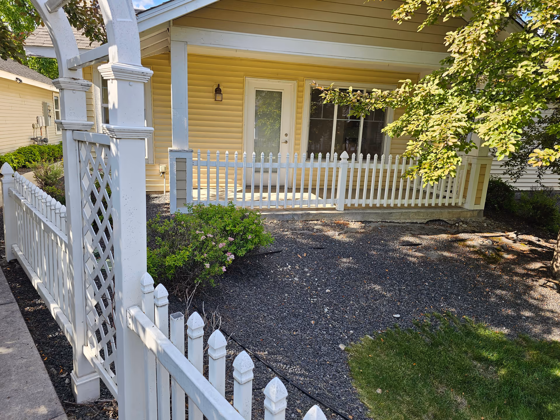 Exterior view of a yellow cottage with a white picket fence and covered porch.