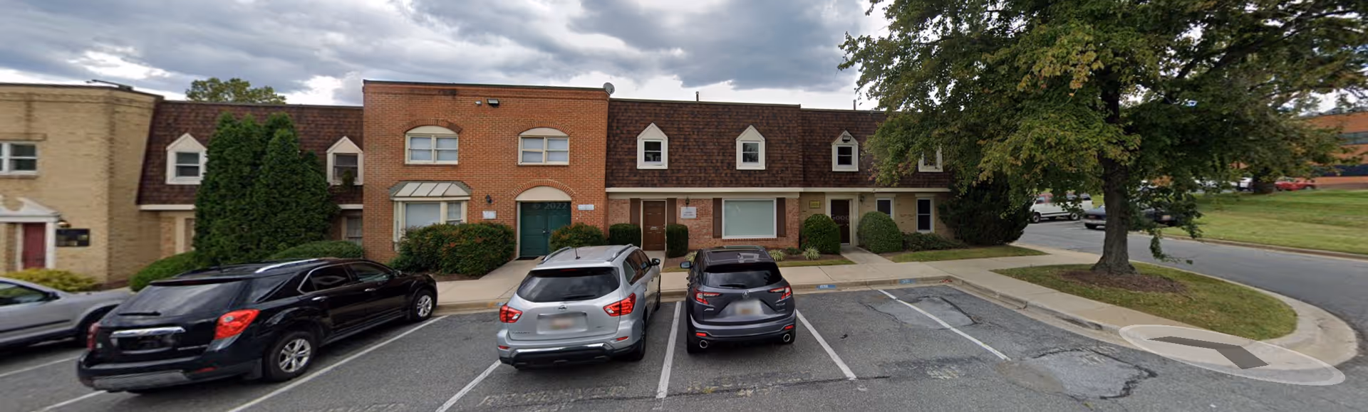 Exterior view of a brick senior care building with parked cars in front