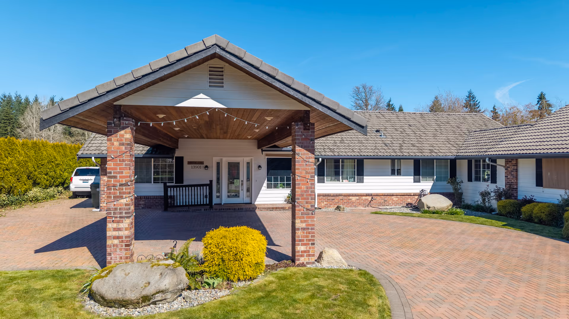 Front view of a single-story senior living facility with a brick entrance canopy and driveway.