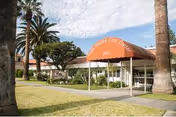 Exterior view of Villa Health Care Center entrance with orange canopy and palm trees.