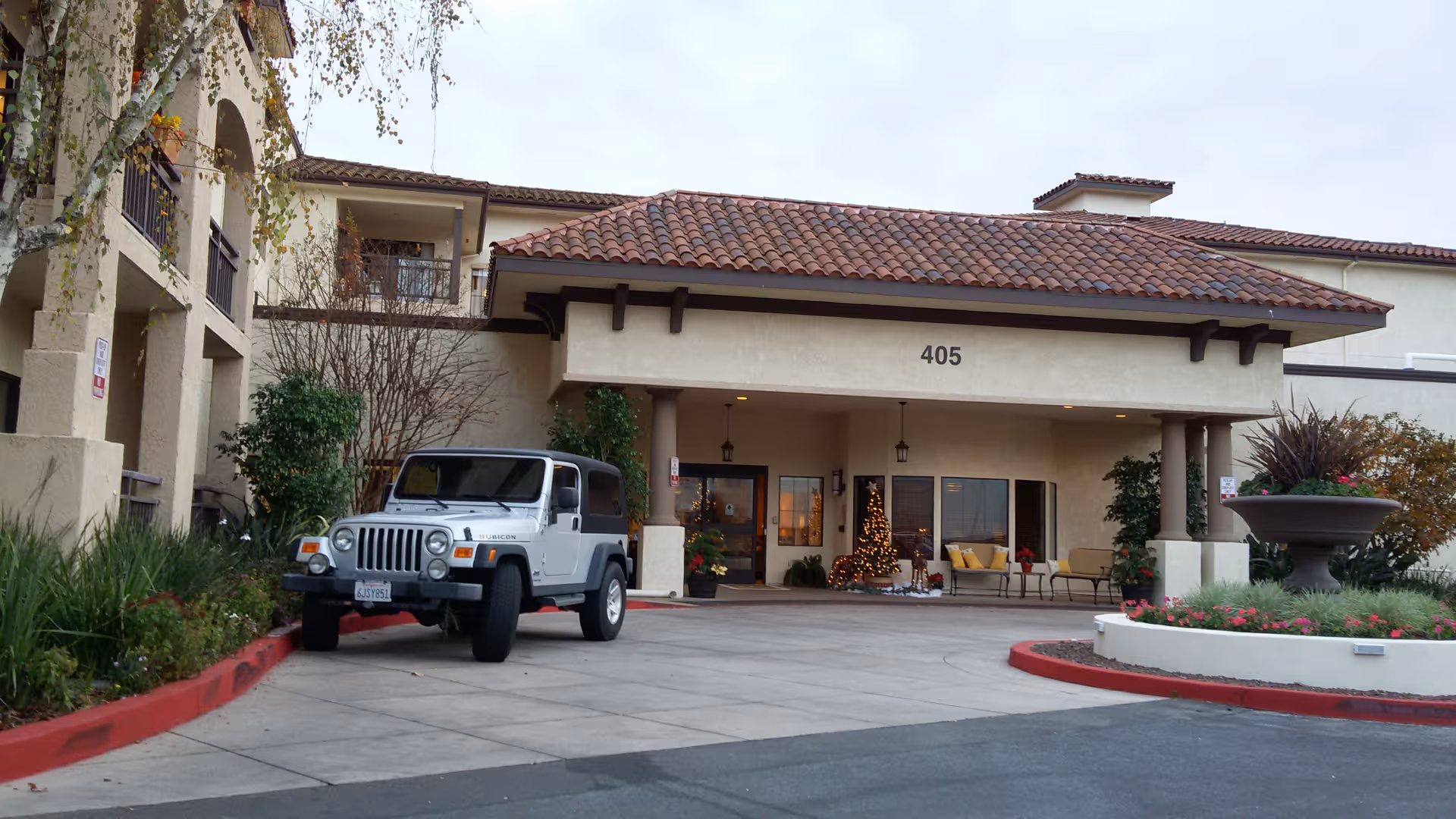 Atria Hillcrest entrance with a driveway, a Jeep parked, and outdoor seating.