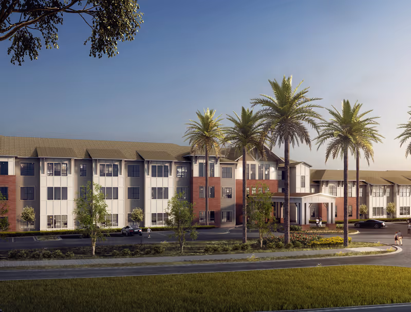 A multi-story senior living building with palm trees and a curved driveway.
