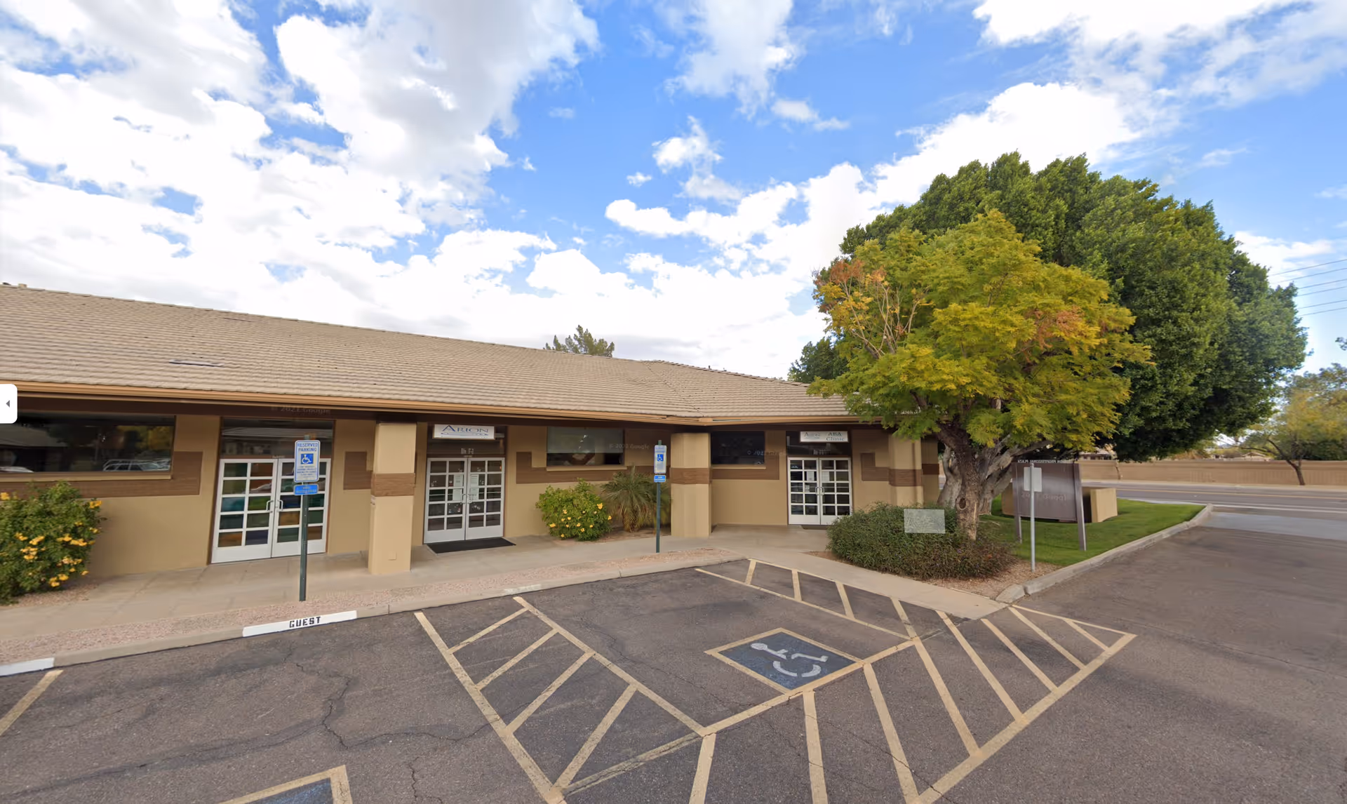 Front of Arion Care Solutions building with entrances, handicap parking, and landscaped trees.