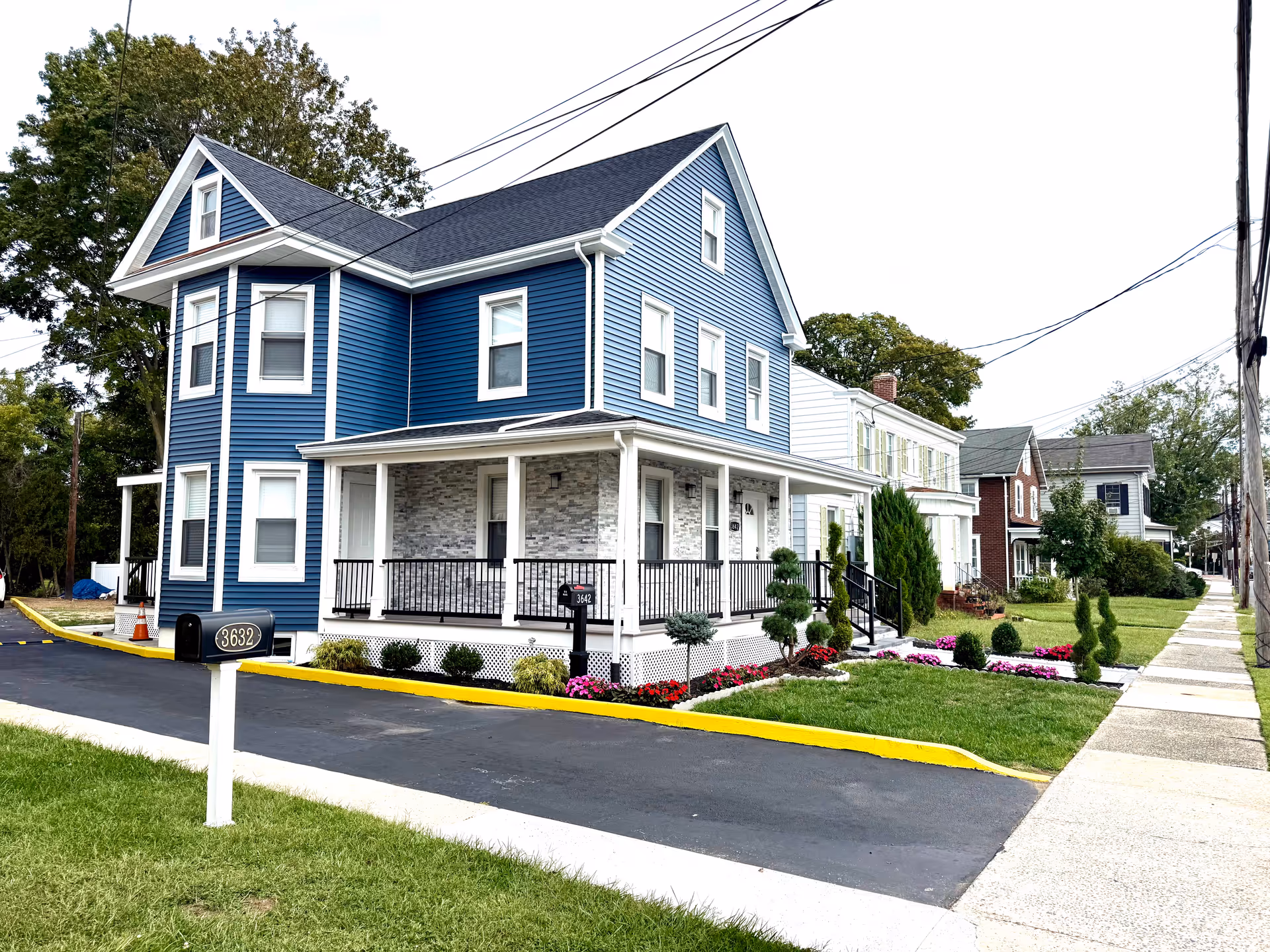Blue two-story building with white trim, front porch, and manicured landscaping.