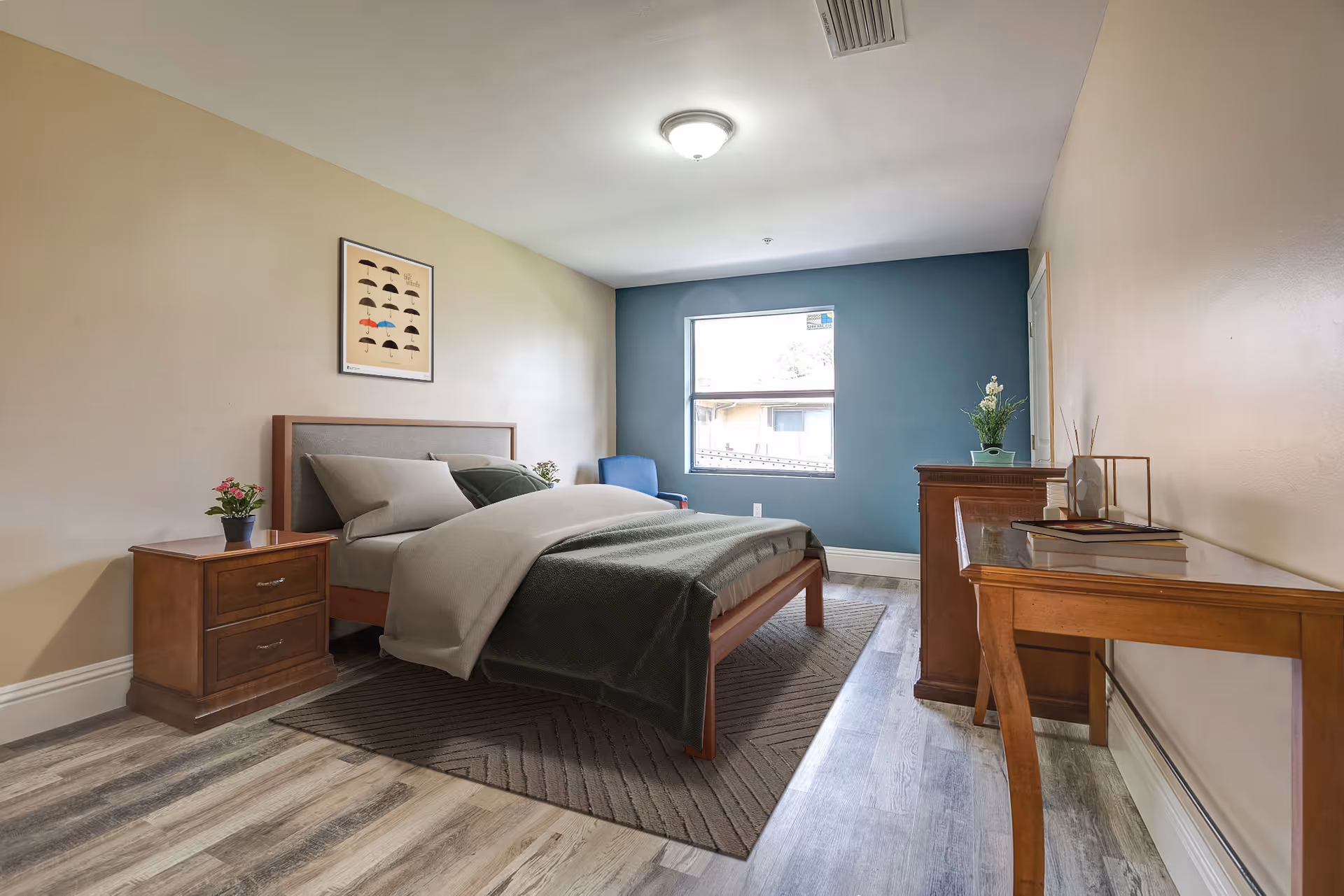 A neatly arranged bedroom in a senior living facility with bed, nightstands, and dresser.