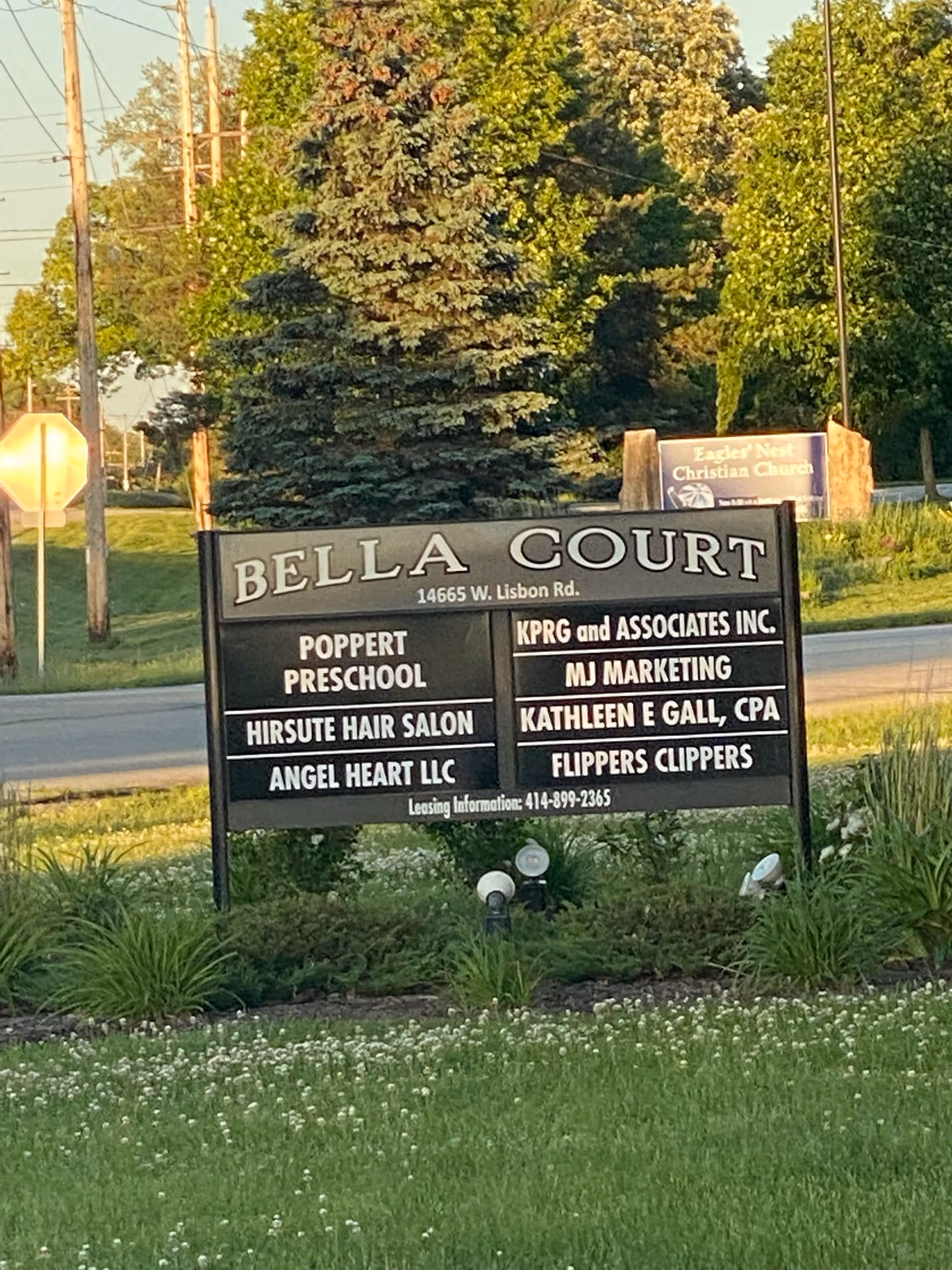 Outdoor signboard at Bella Court listing Angel Heart LLC among neighboring tenants.