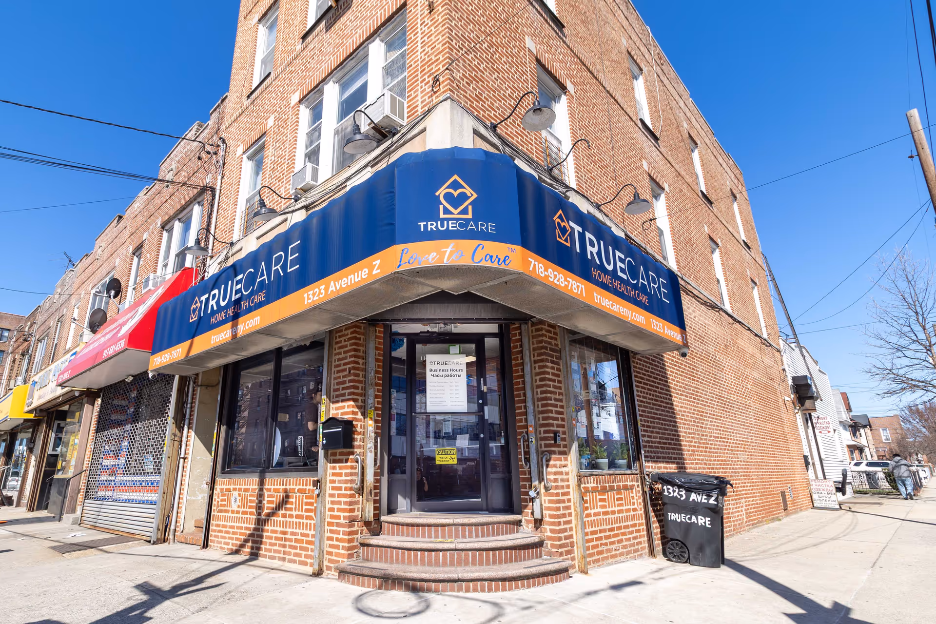 Corner brick building with a blue TrueCare awning and storefront entrance.