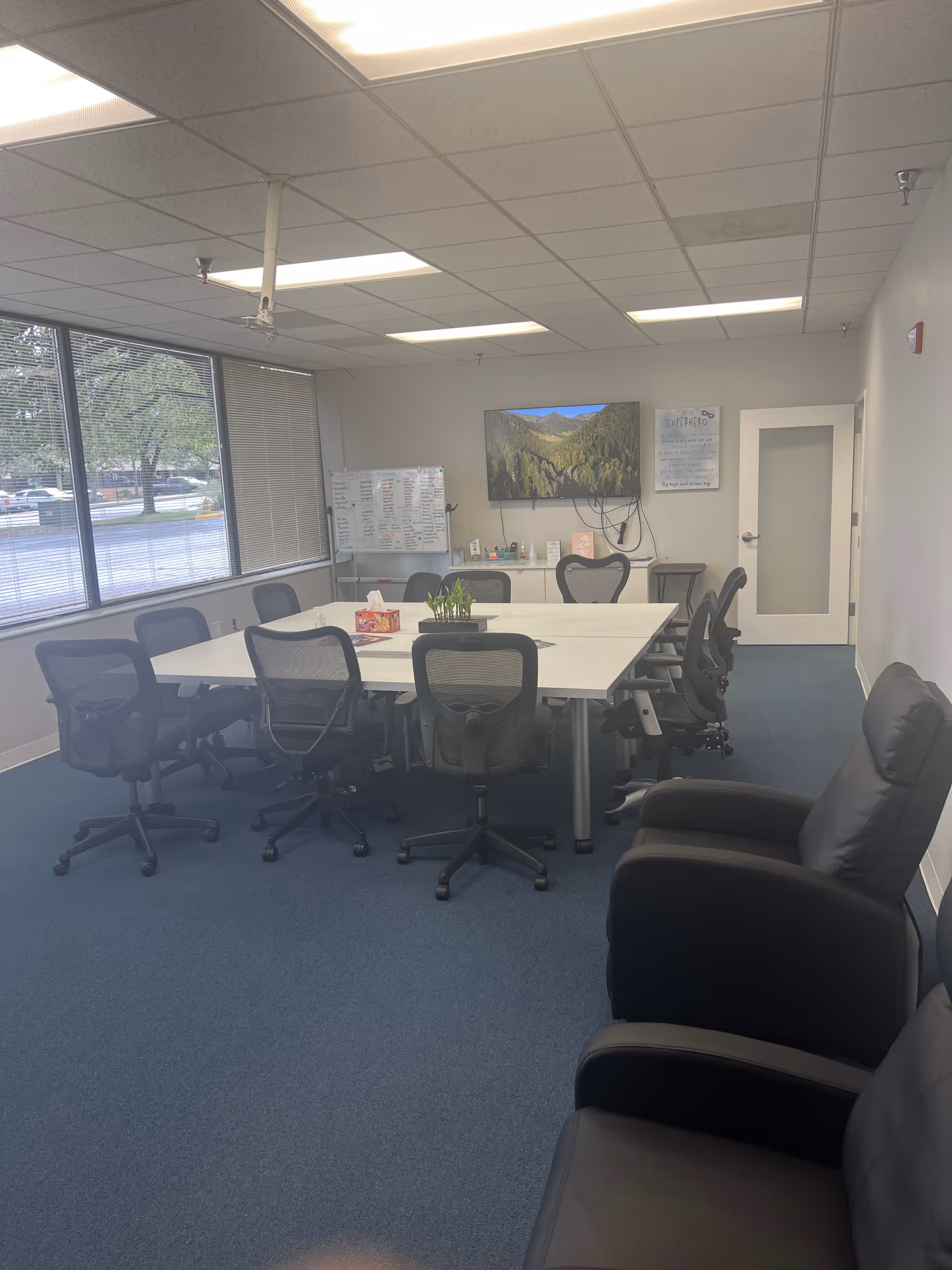 Large conference room with a white table, multiple chairs, and windows.