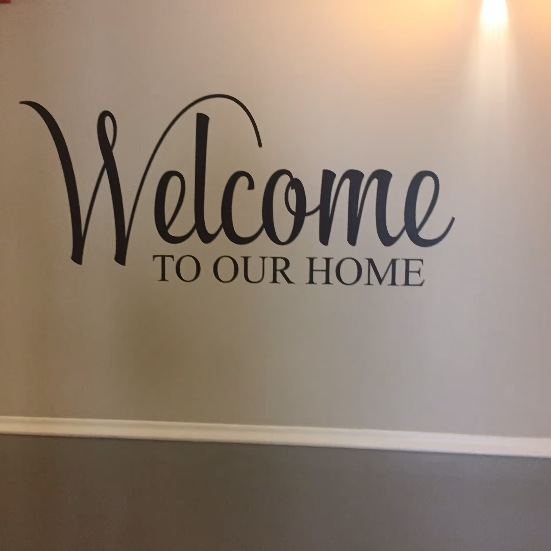 Interior wall featuring a large Welcome to our home sign in a hallway.