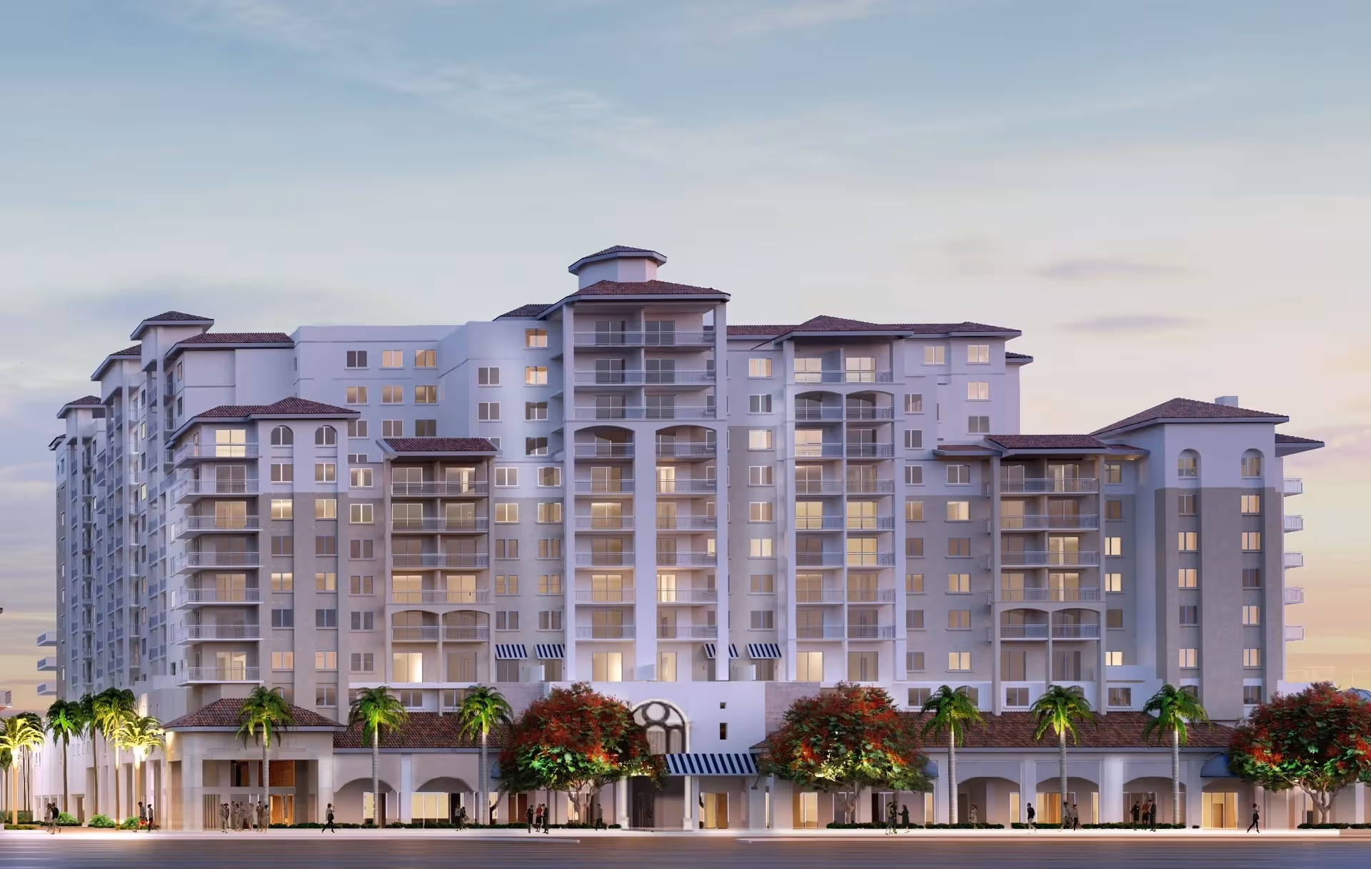 A large multi-story senior living building with balconies and palm trees at dusk.