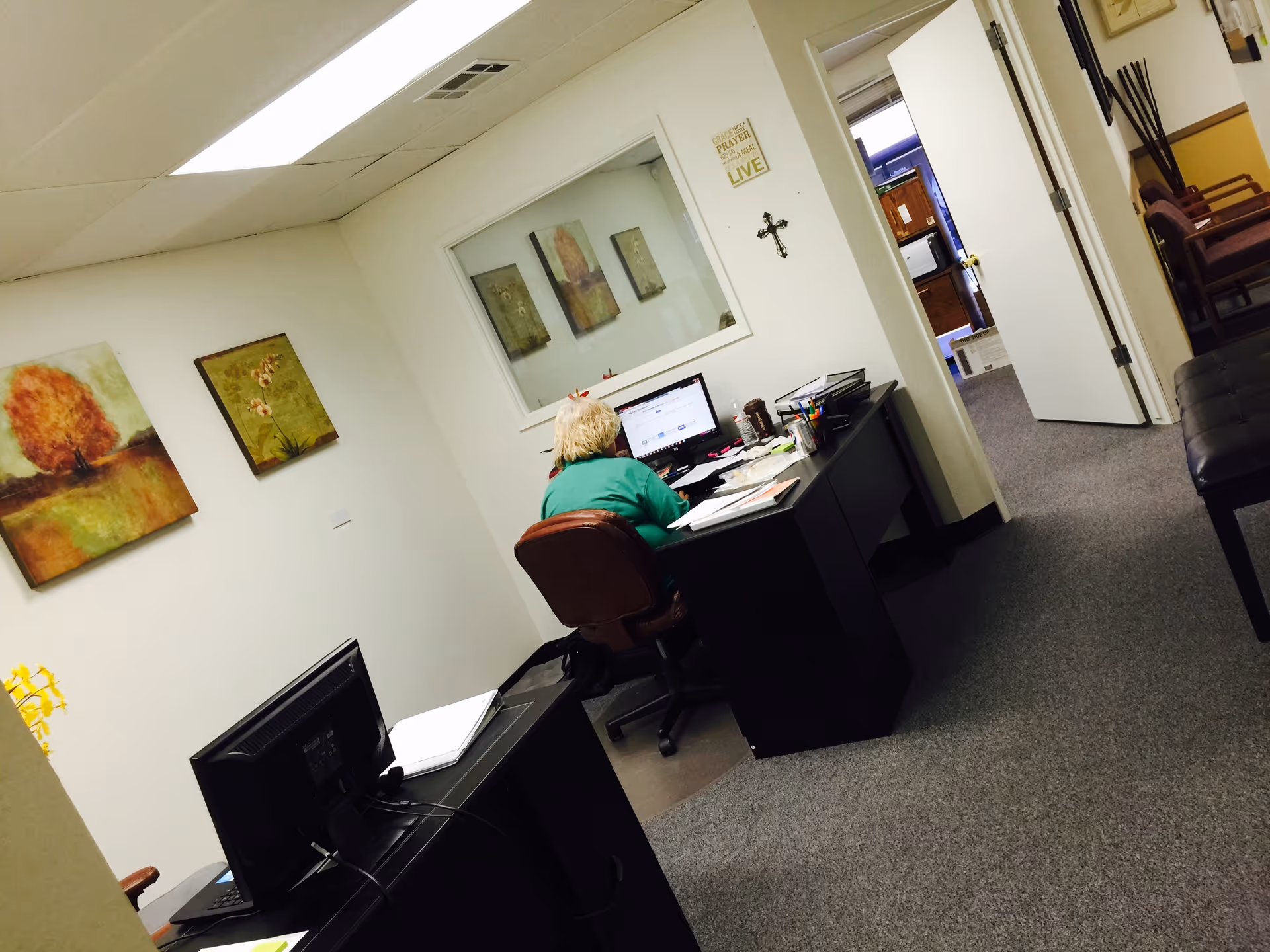An office desk area inside Fresno Yosemite Health Care with computer and wall art.