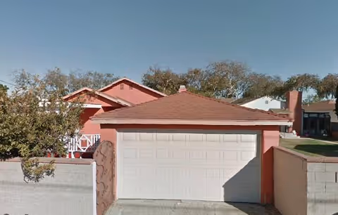 Front view of a peach-colored residential building with a white garage door.