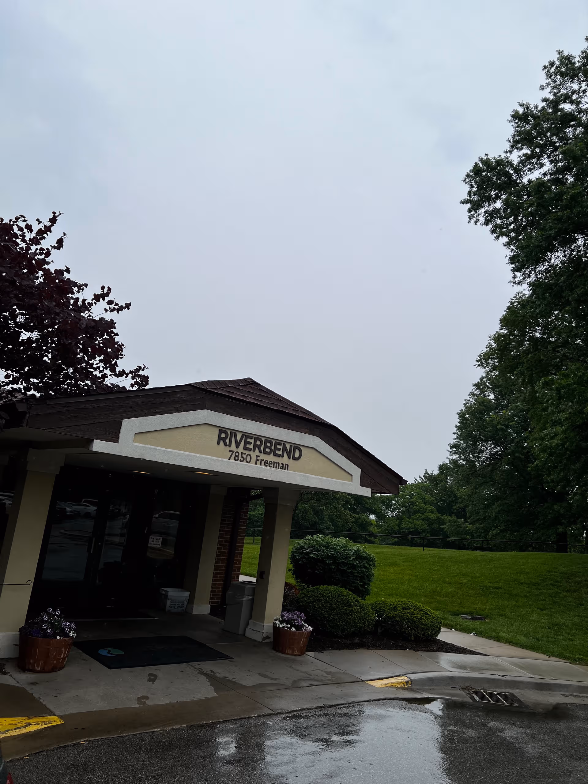 Riverbend building entrance with sign, pillars, and manicured landscaping in front