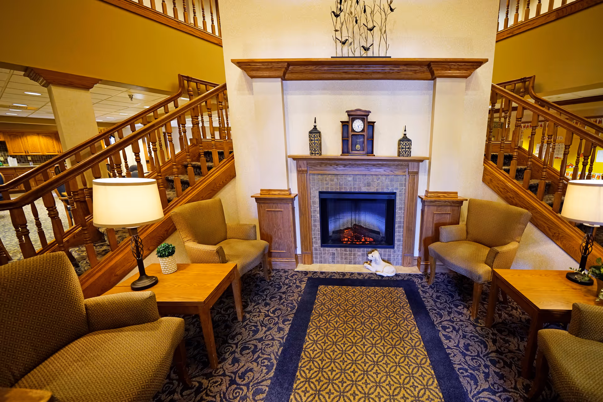 Cozy interior lobby area with a central fireplace, armchairs, and lamps.