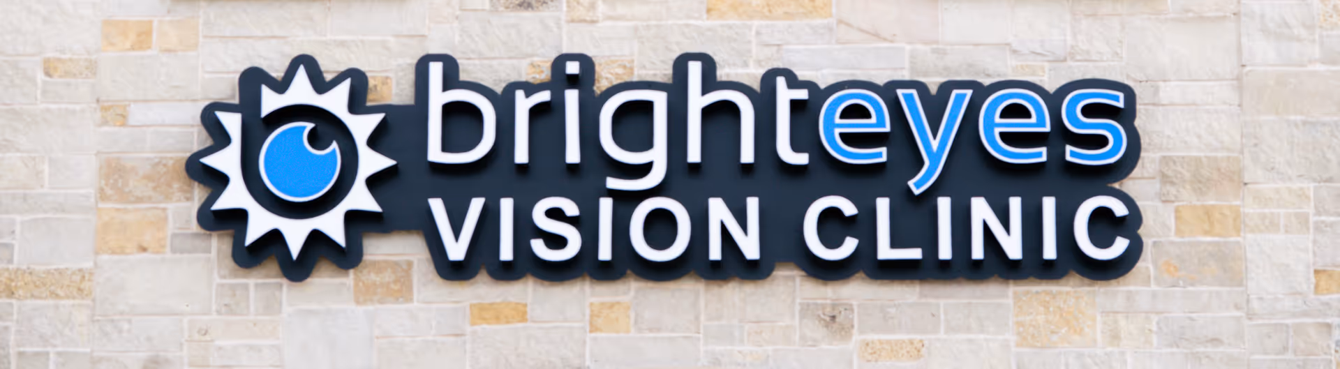 Exterior view of Bright Eyes Vision Clinic sign on a stone building facade.