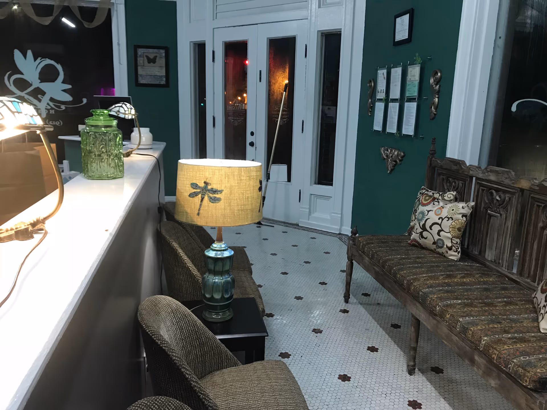 Cozy interior lounge with a white front desk, green wall, and vintage seating.