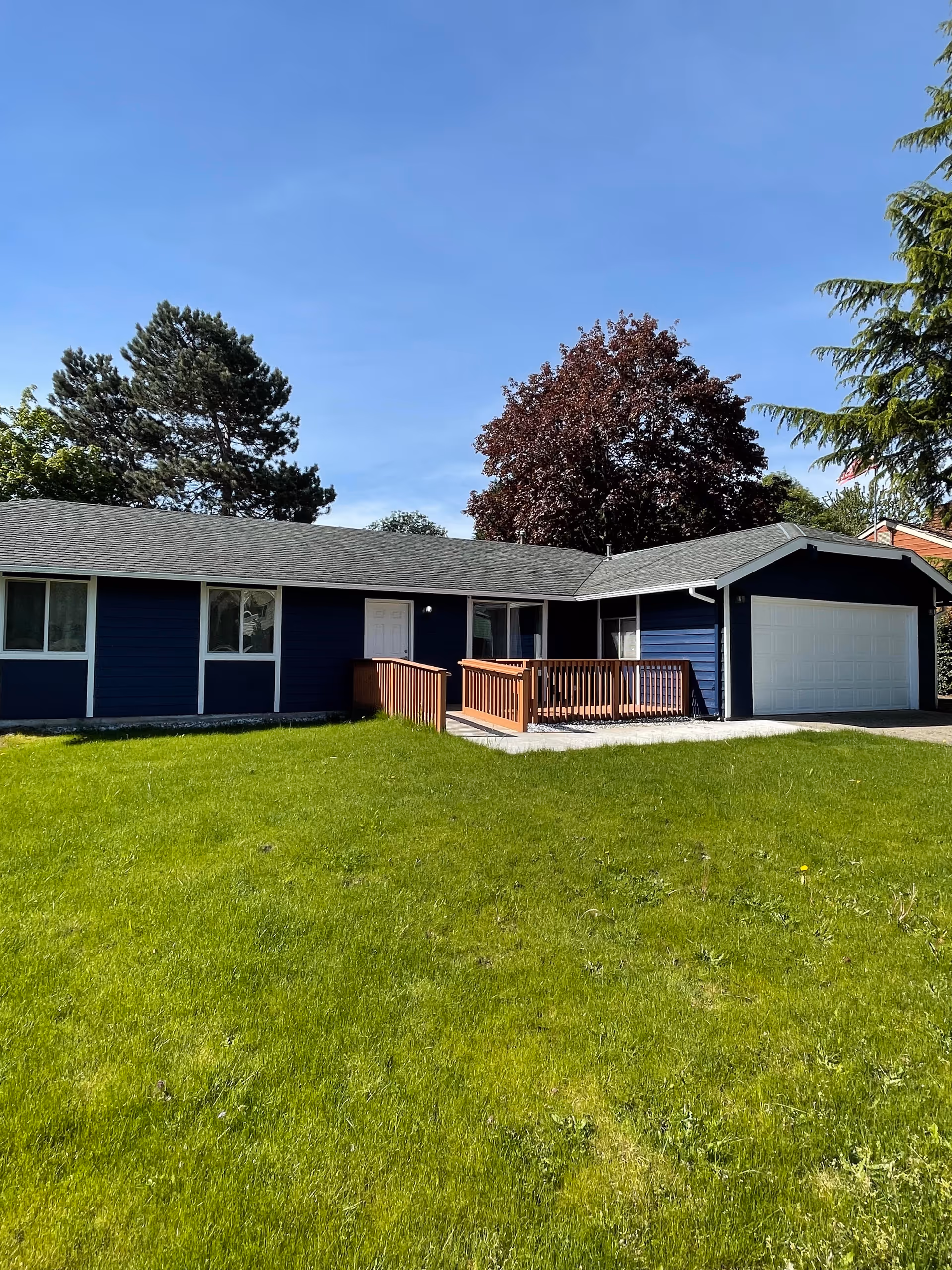 Blue single-story house with front porch, attached garage, and green lawn.