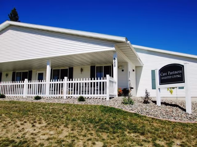 White single-story senior living facility with a front porch and picket fence