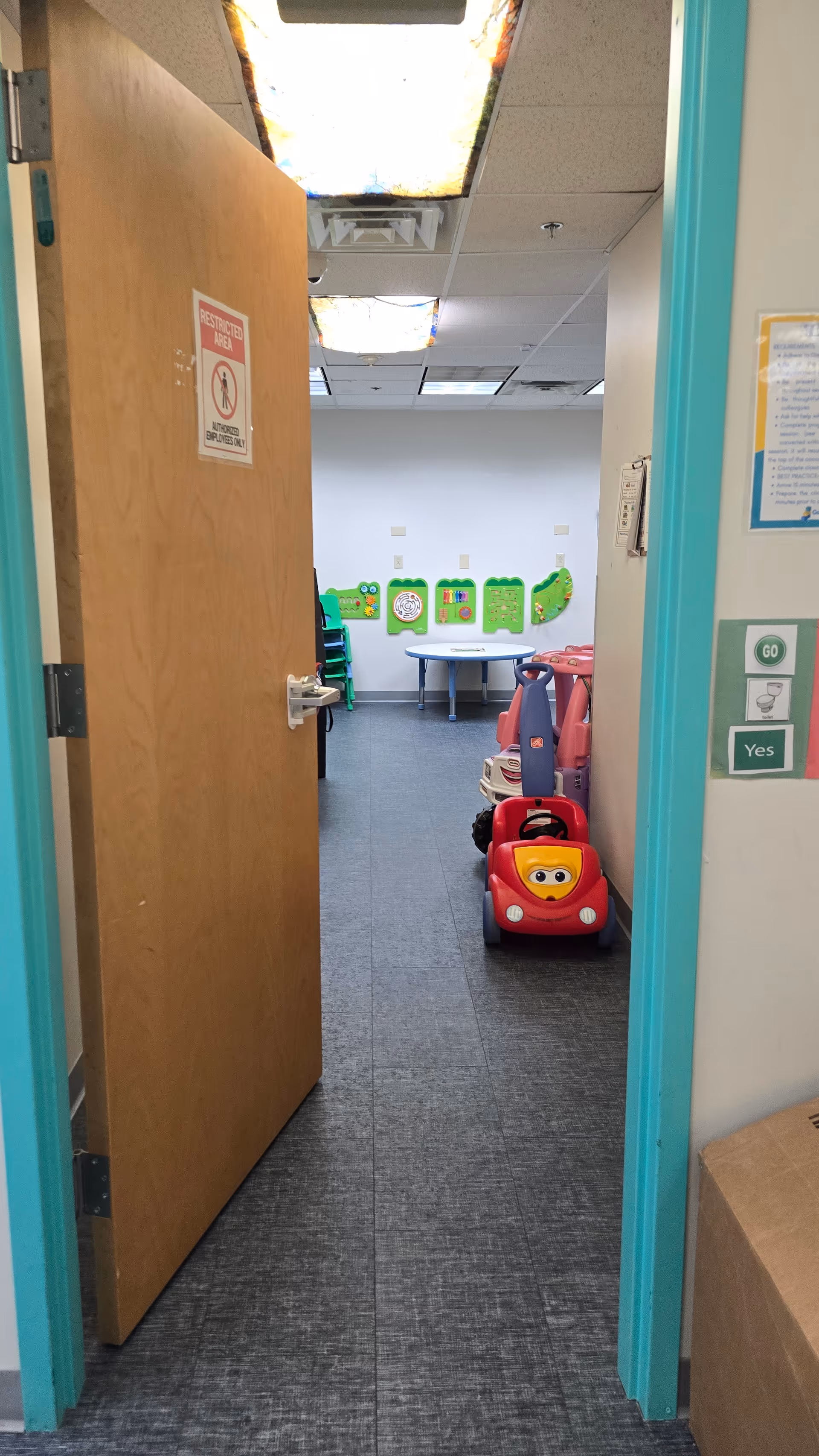 A doorway opens into a children's play area with a table and colorful toy car.
