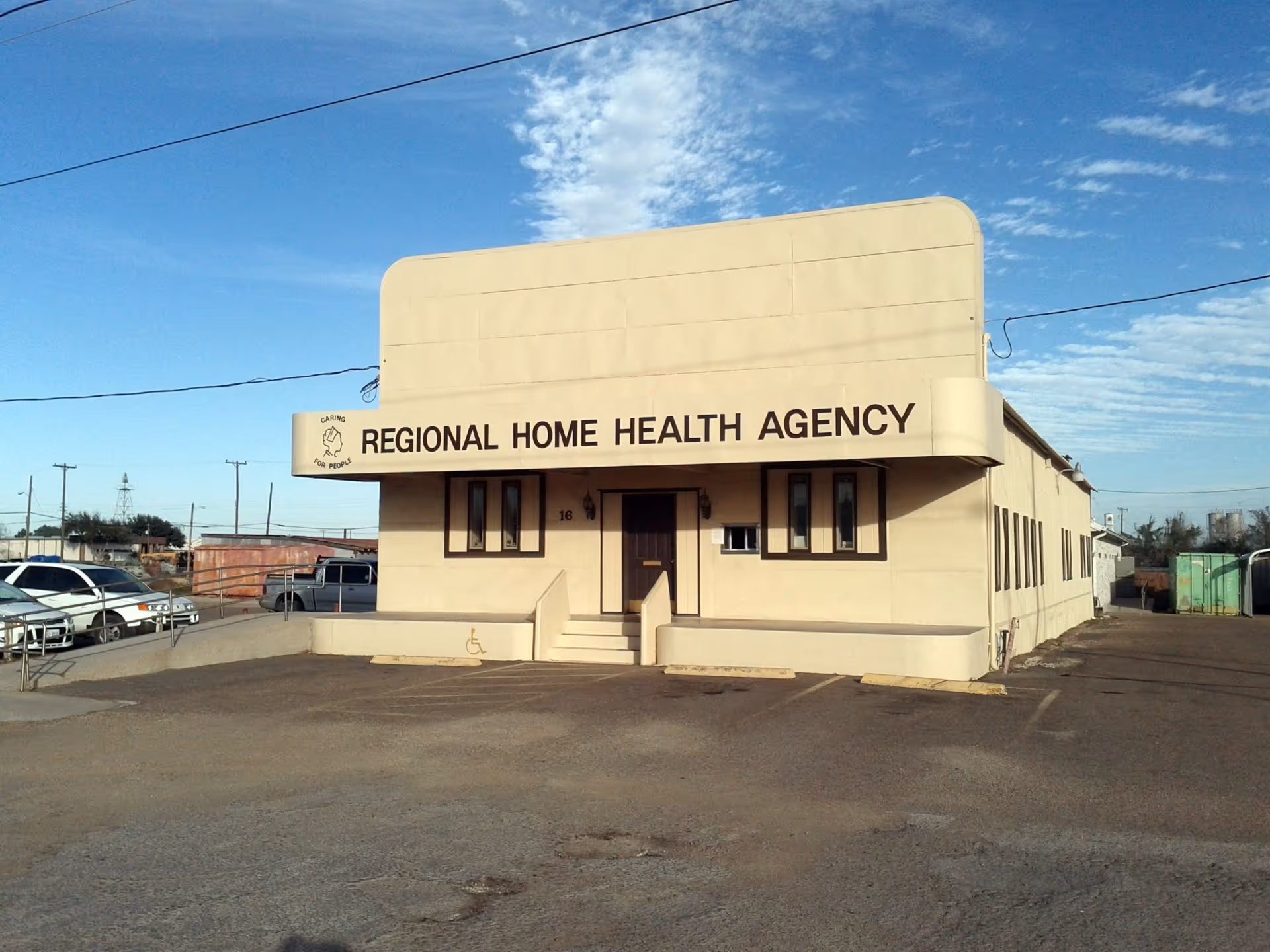 Beige Regional Home Health Agency building with a sign, parking lot, and blue sky.