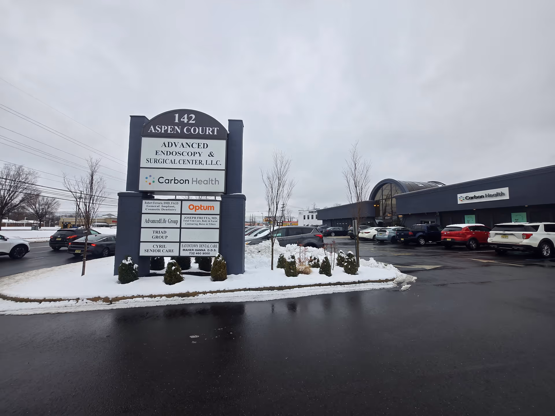 Exterior view of Cyril Senior Care sign and surrounding plaza in snowy parking lot.