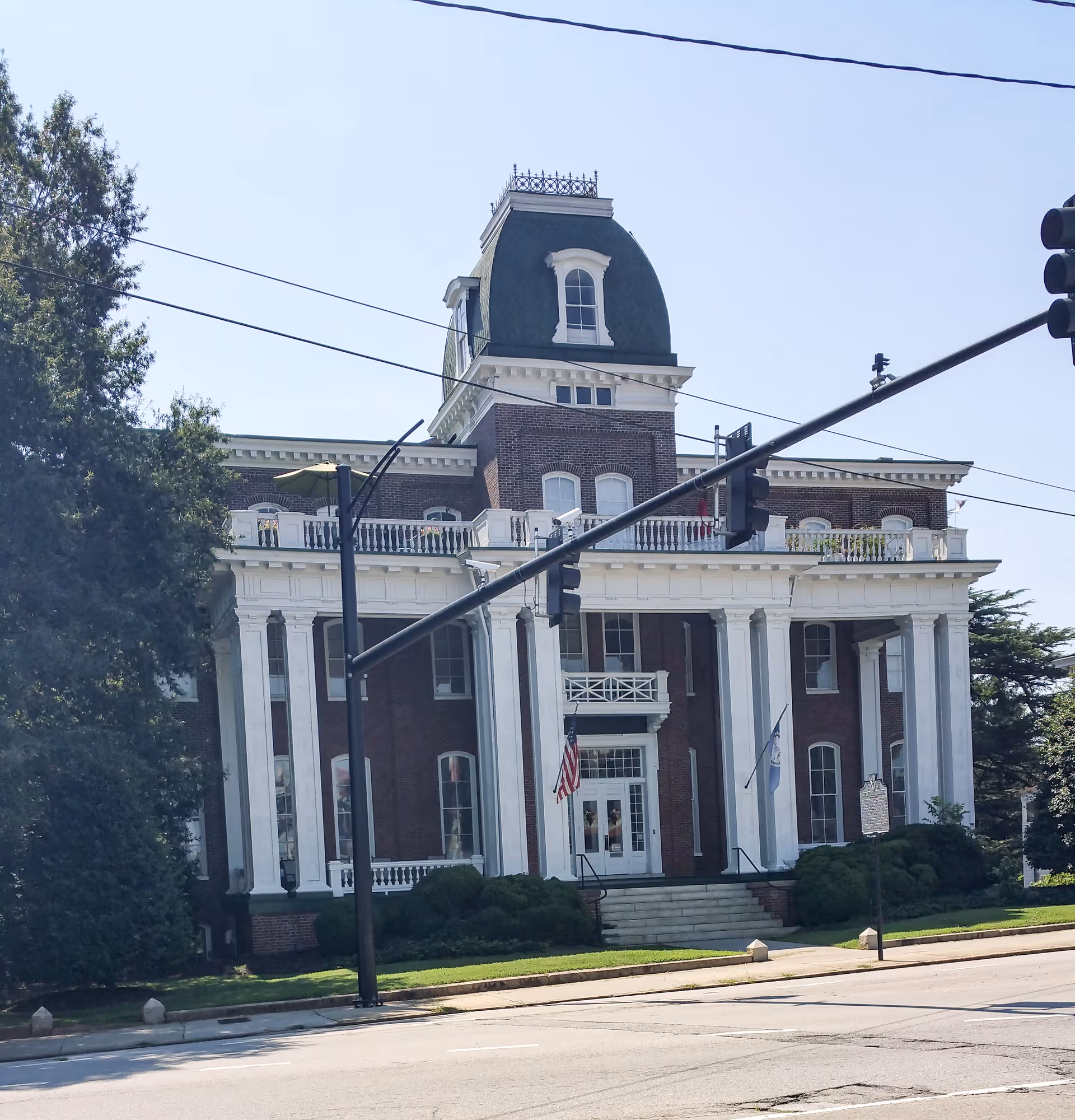 Historic brick building with white columns and a domed roof, facing a street.