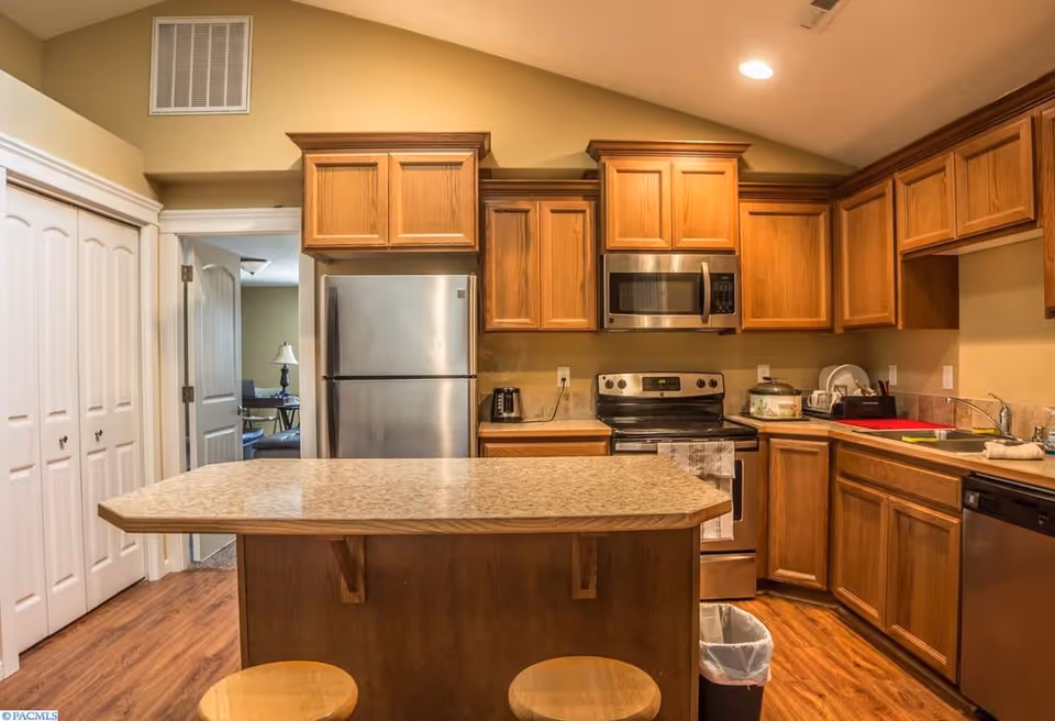 Modern kitchen in a senior living facility with wooden cabinets, stainless appliances, and island.