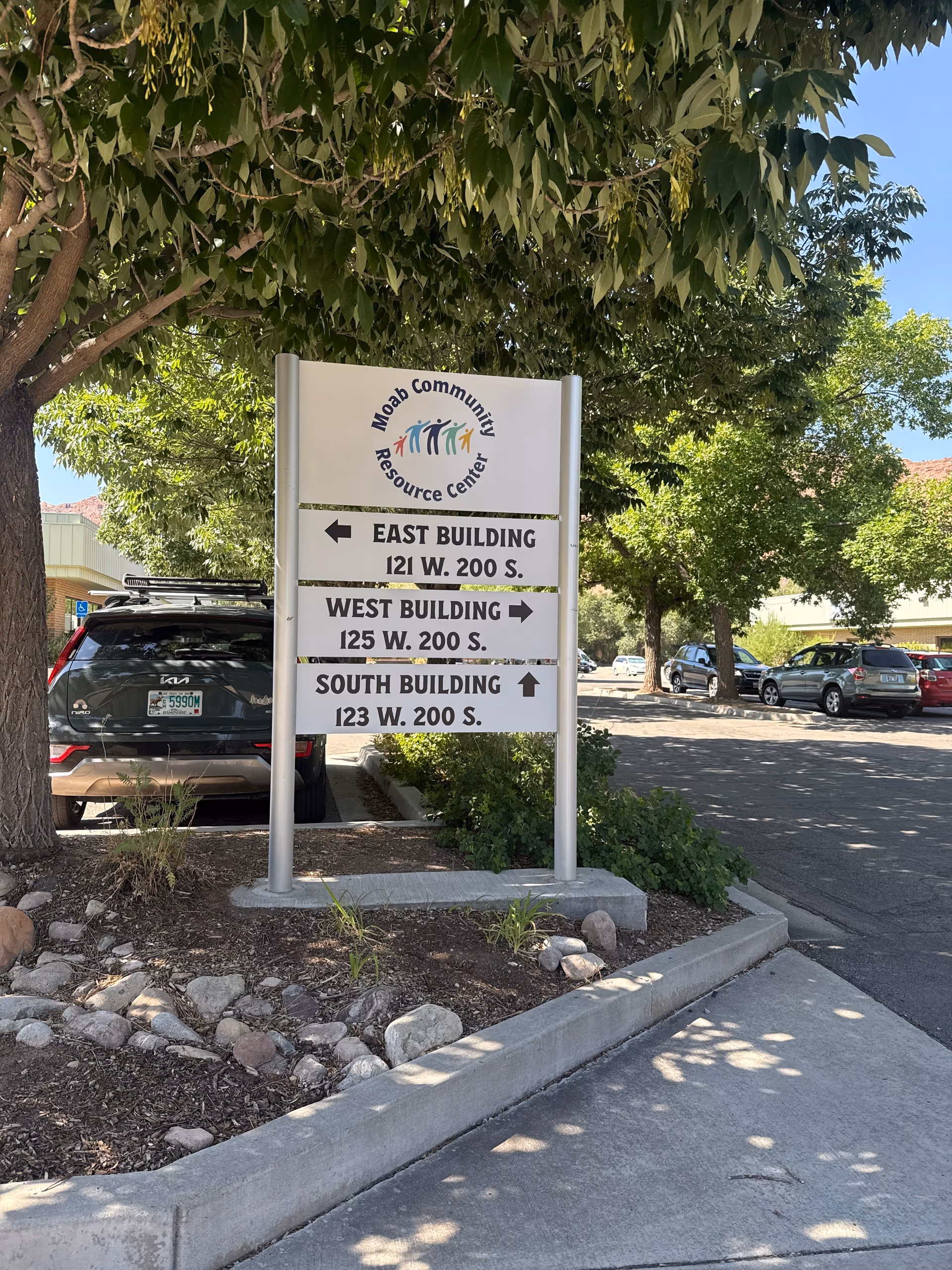 Signboard in a parking lot lists East, West, and South buildings at Moab Community Resource Center