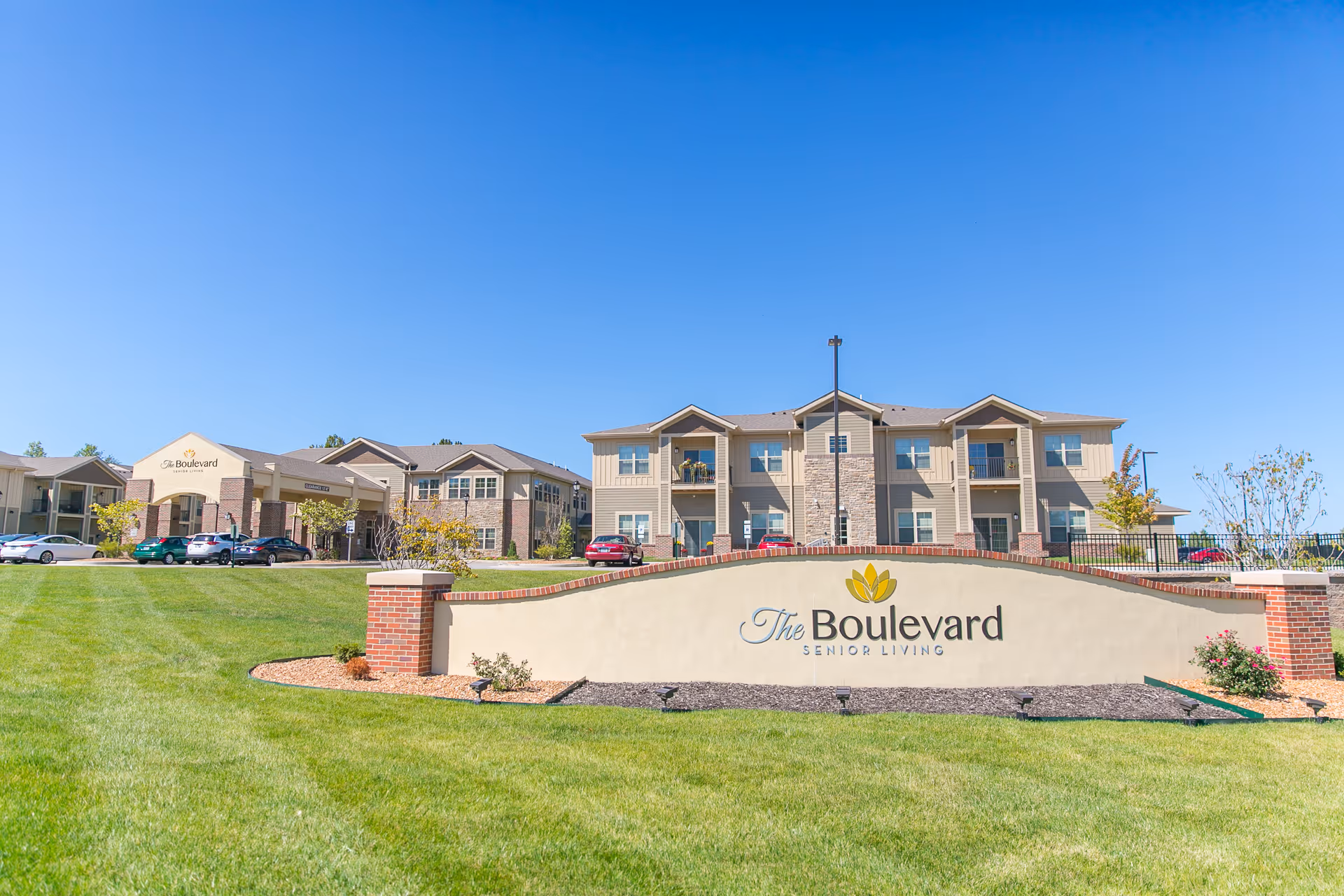 Exterior view of The Boulevard Senior Living of Saint Charles with a lawn and sign.