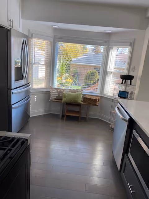 Bright kitchen with stainless steel appliances and a window nook with plants.
