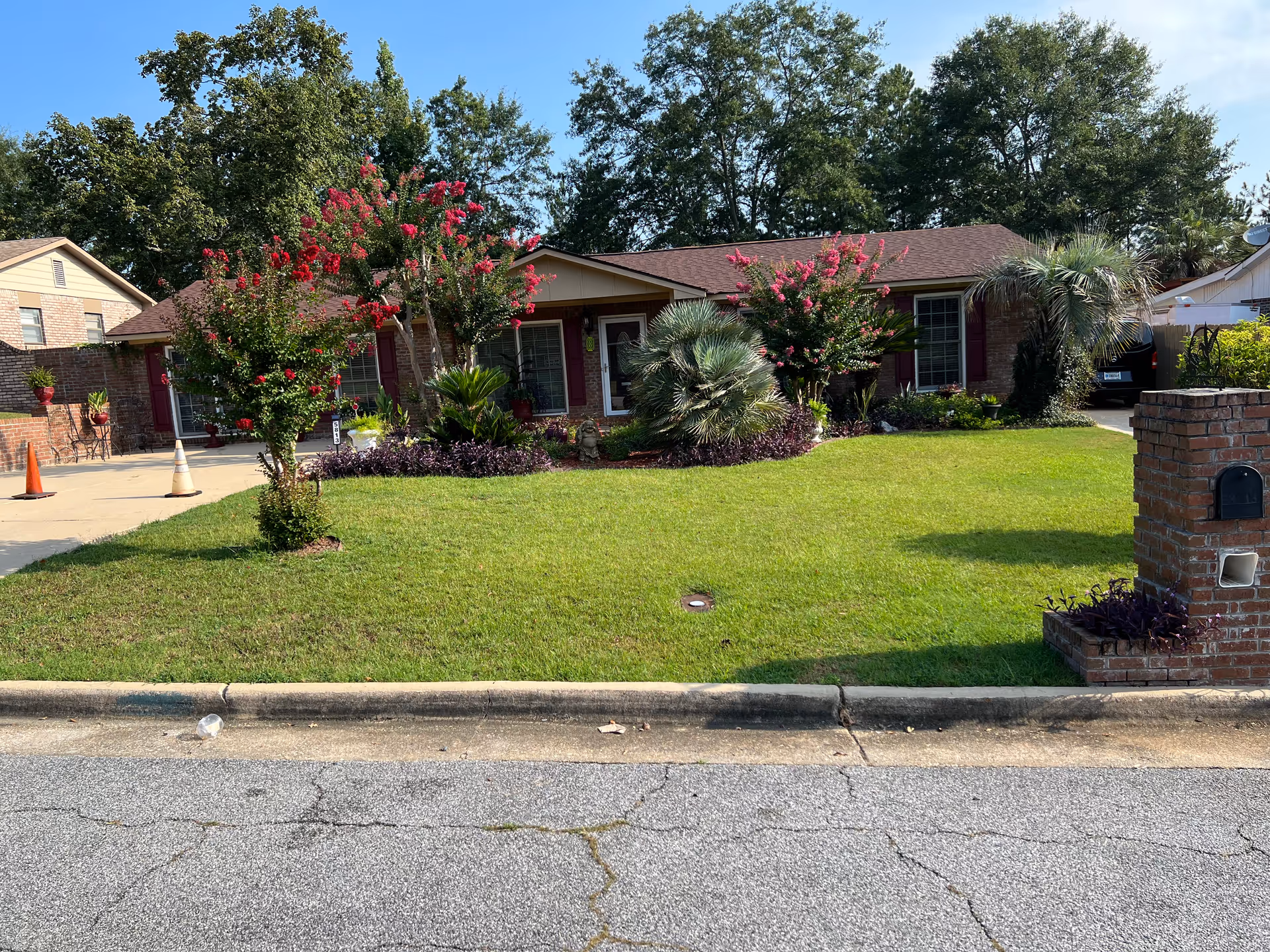 Single-story senior home with a manicured front lawn and colorful shrubs.