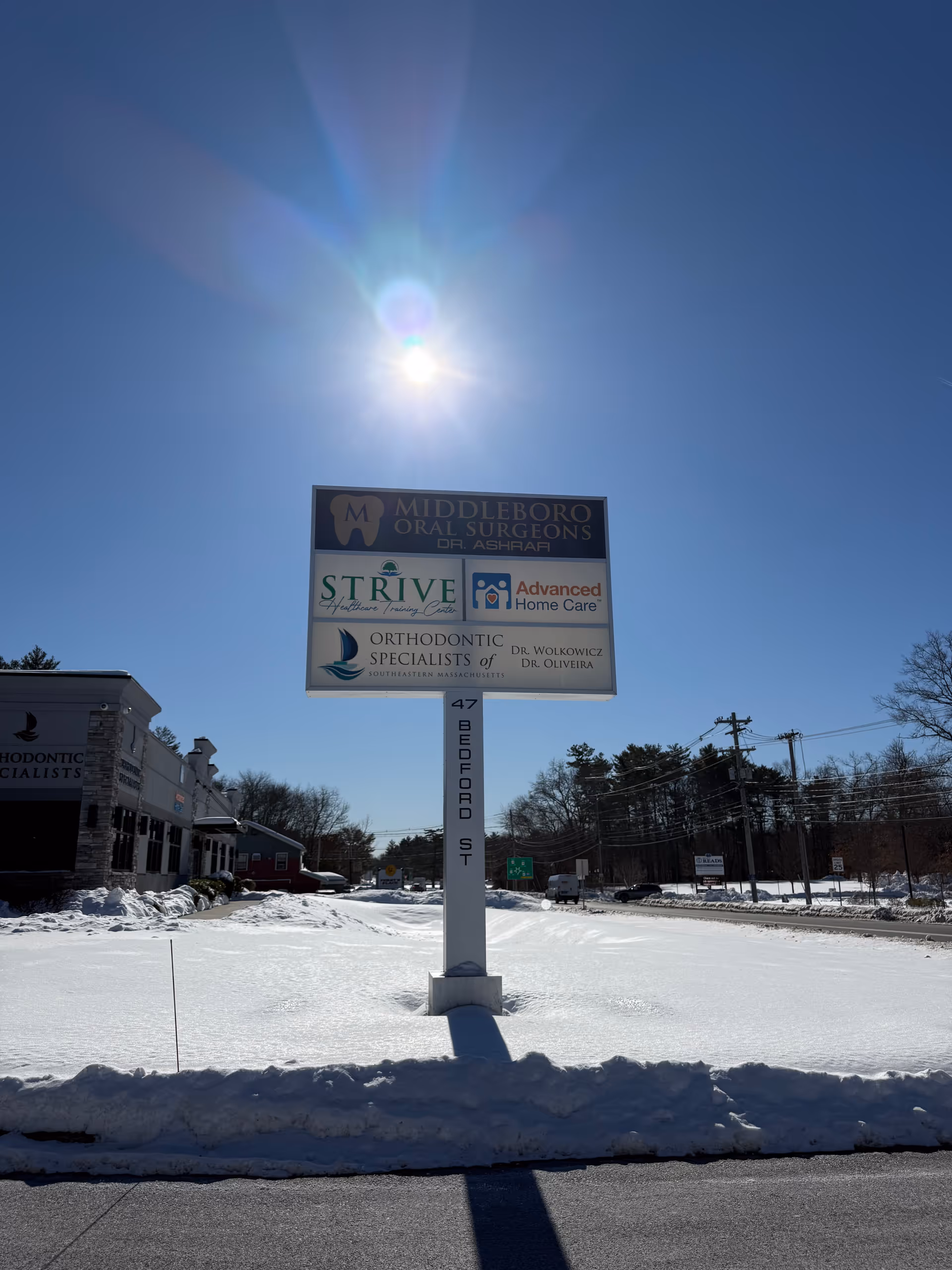 Sunny exterior with a tall multi-tenant sign advertising Advanced Home Care Services on a snowy lot