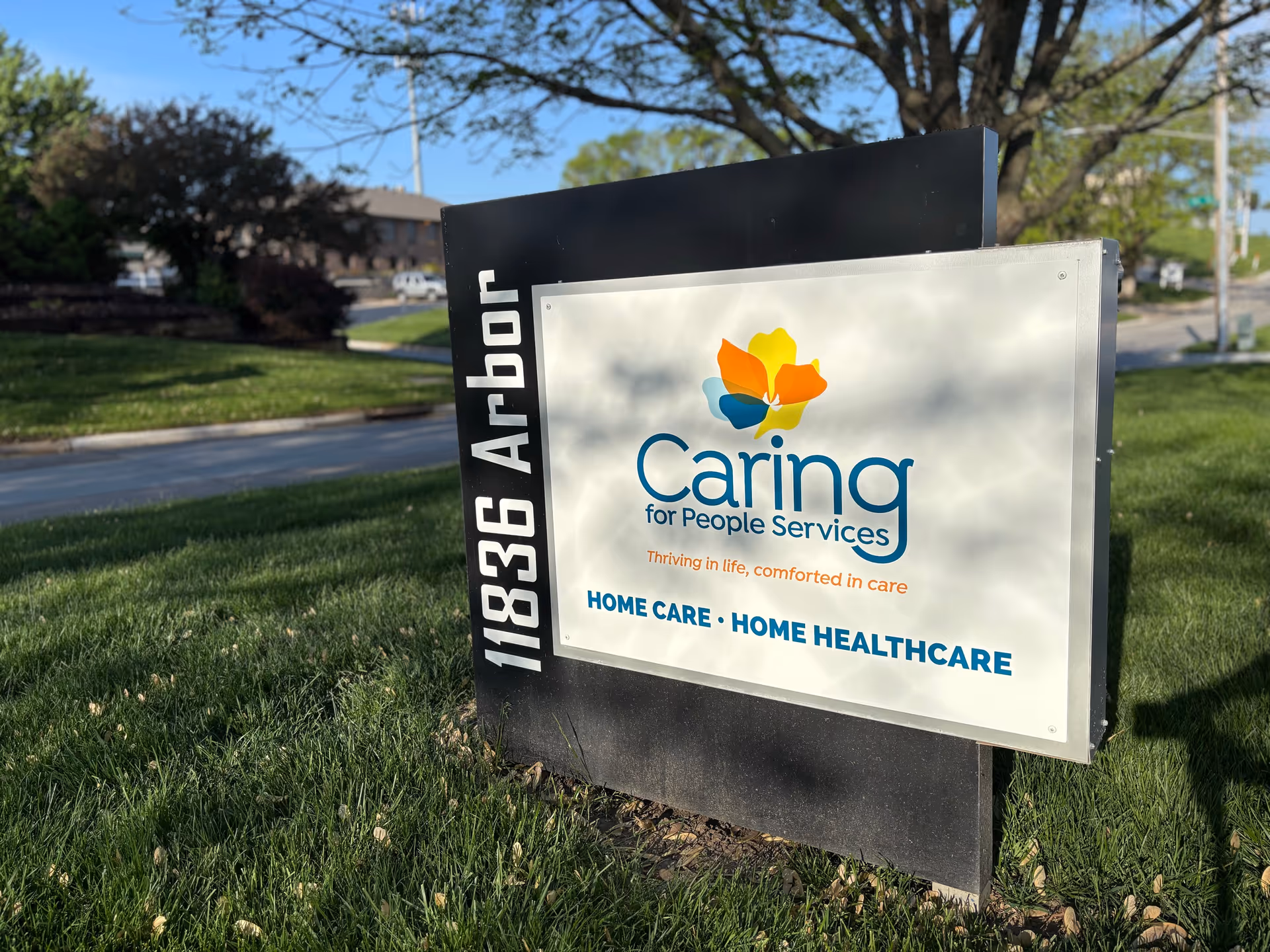 An exterior sign for Caring for People Services on a grassy area.