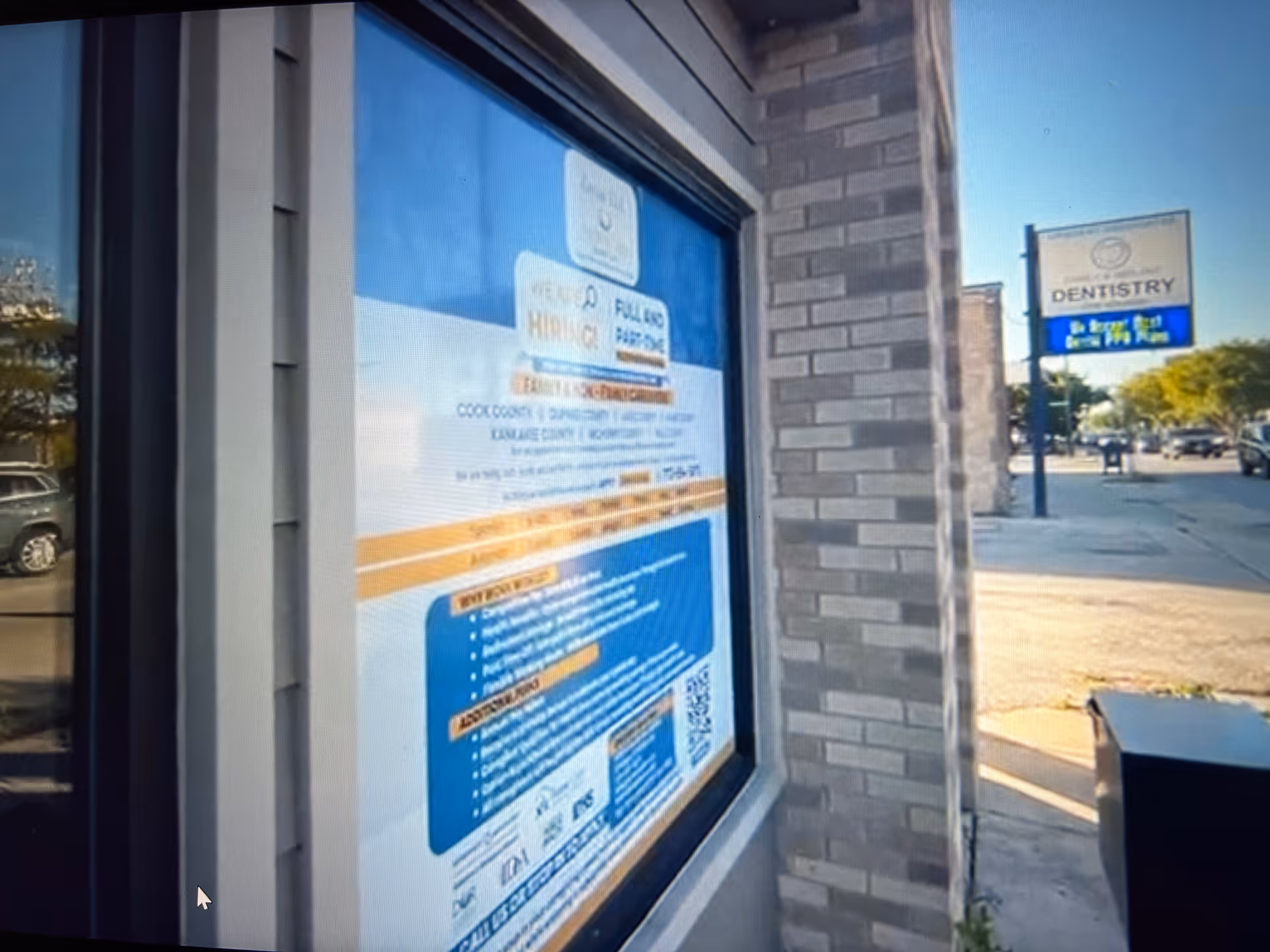 Exterior brick building with a large window poster and street-side dentistry sign.