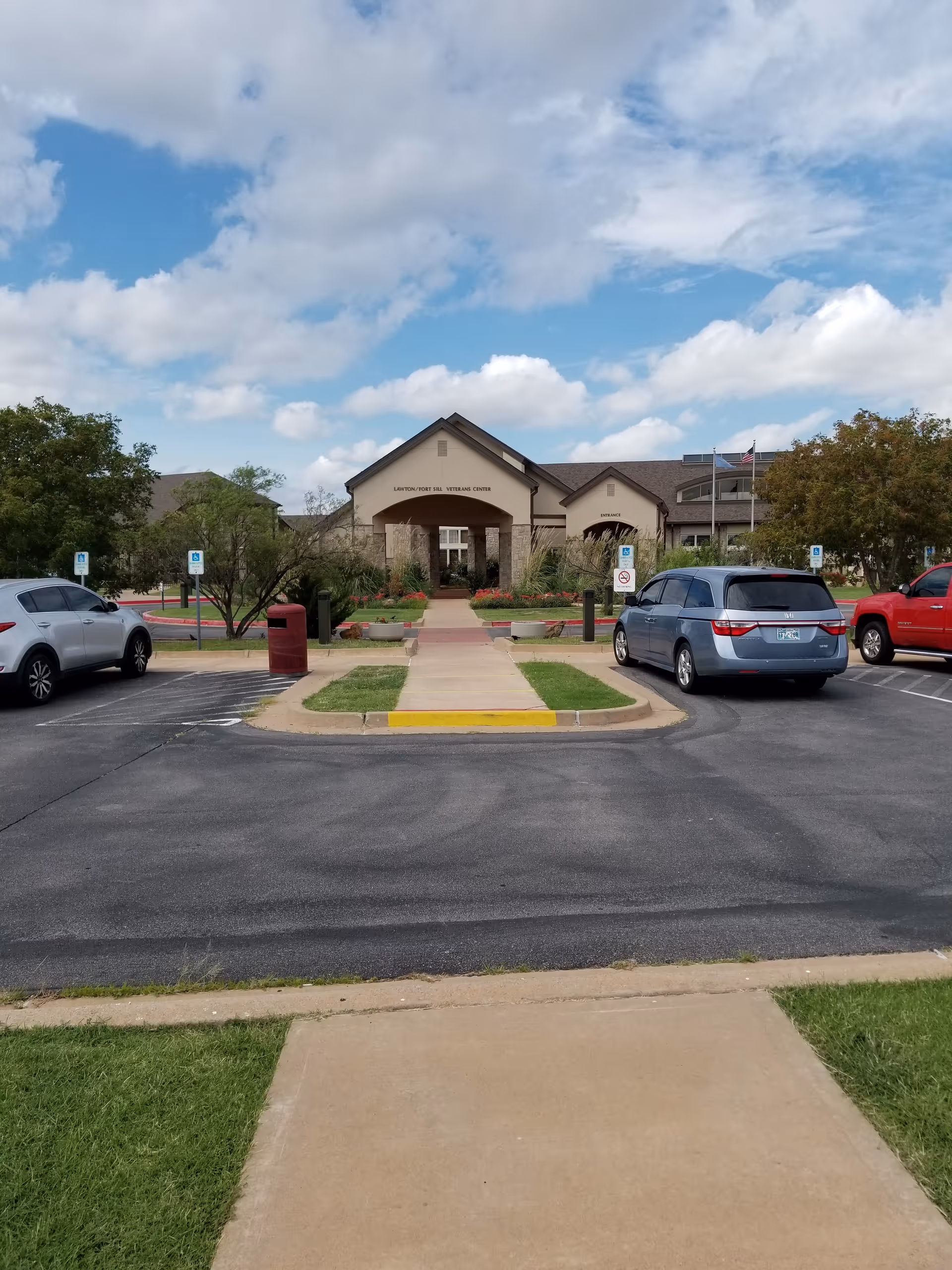 Front entrance of Lawton Fort Sill Veterans Center with parked cars and clear sky