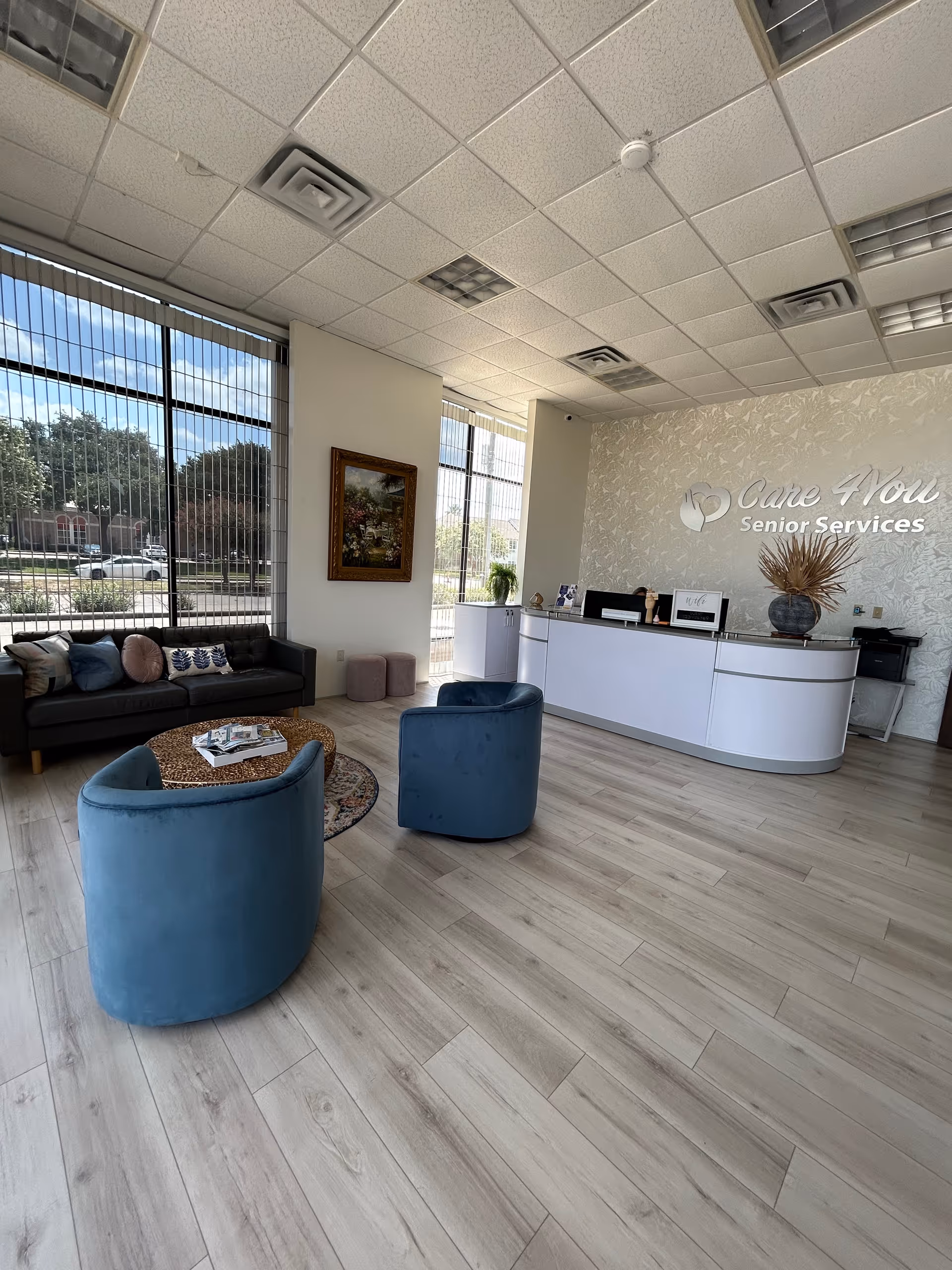 Modern lobby with blue chairs, large windows, and a curved white reception desk.