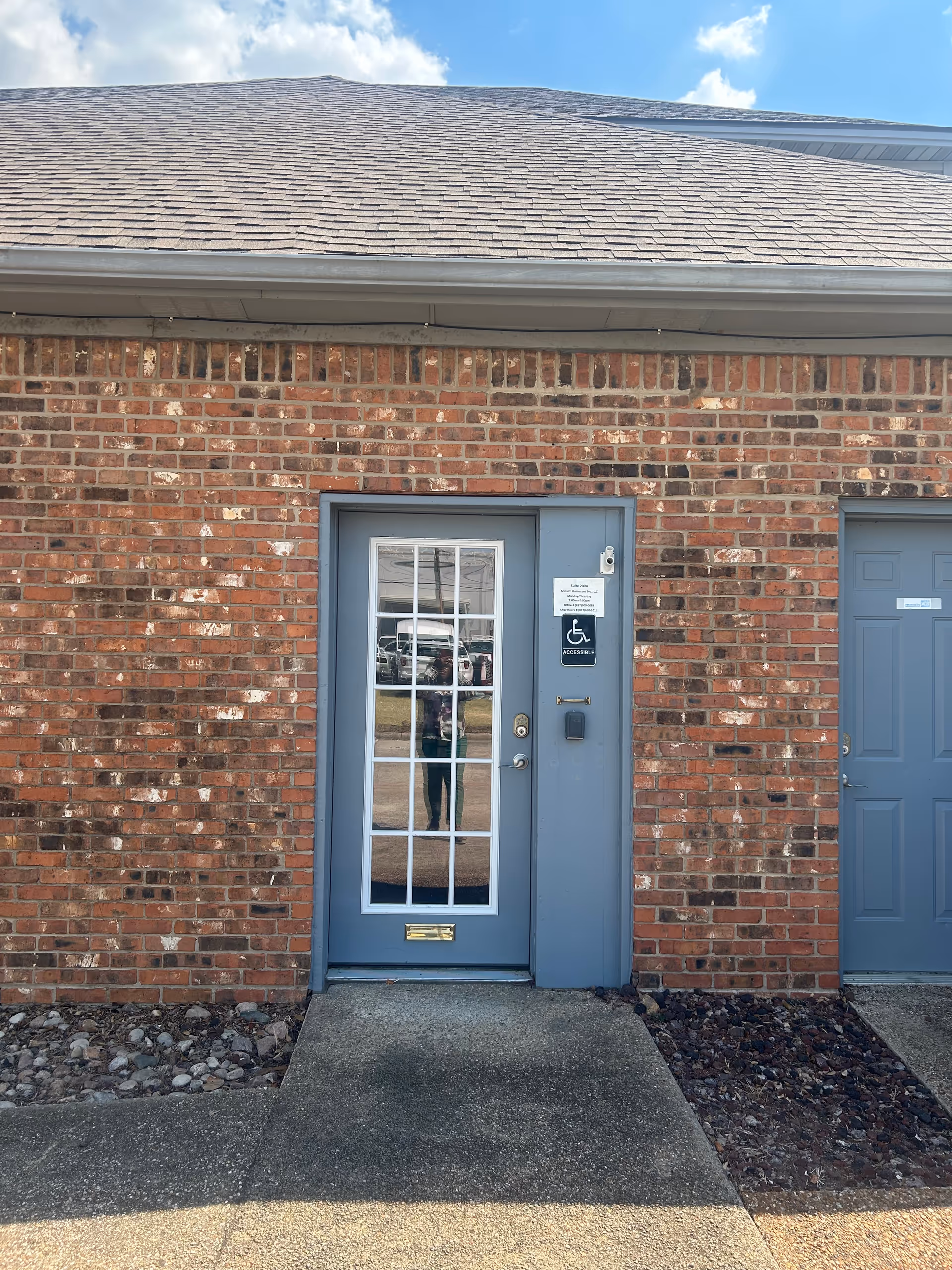 Brick exterior with blue door, wheelchair accessibility sign, and a second door on the front.