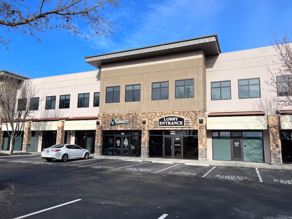 Exterior view of a storefront building with a lobby entrance and parking lot.