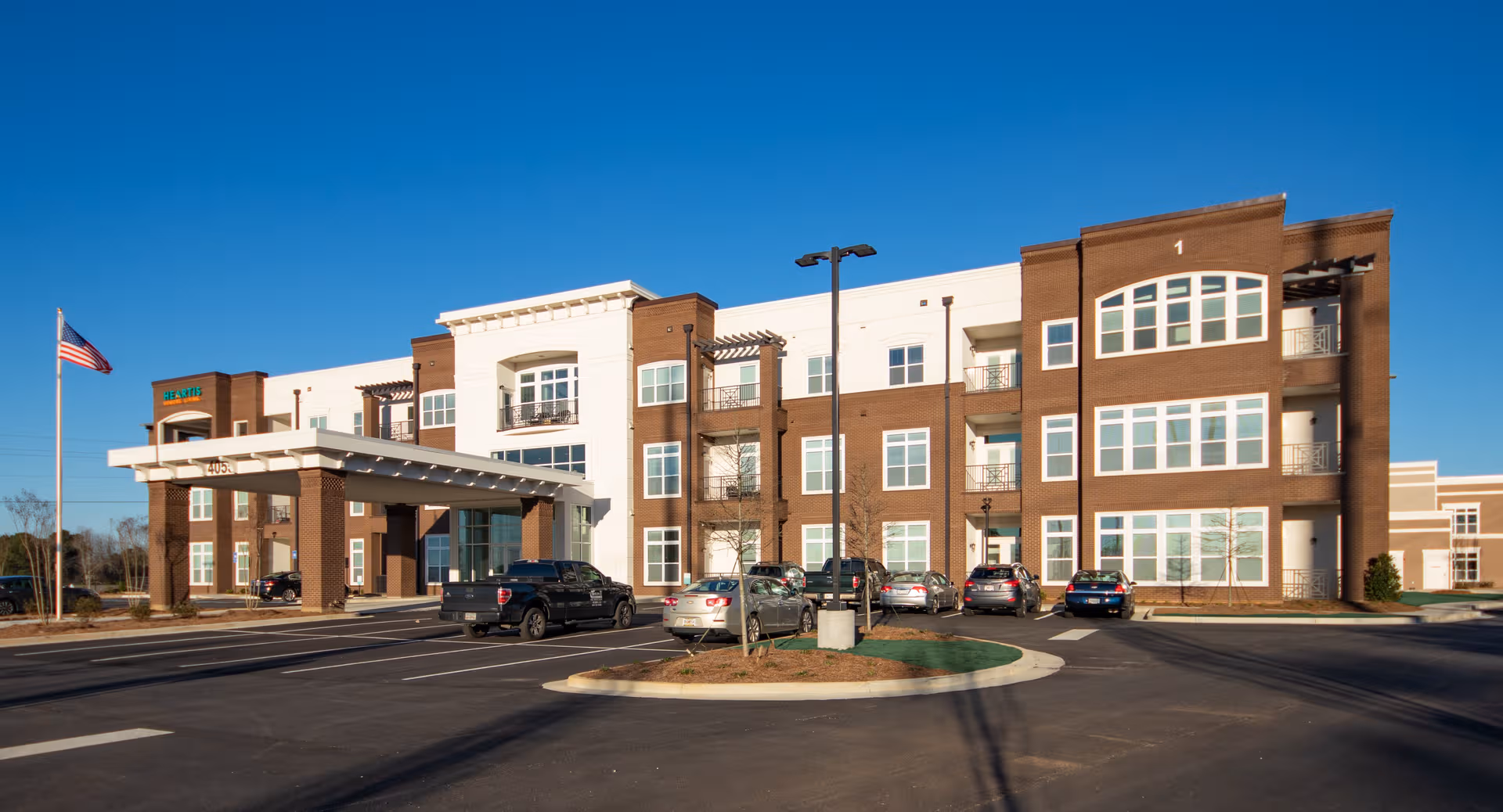 Exterior view of Heartis Suwanee Senior Living building with entrance and parking.