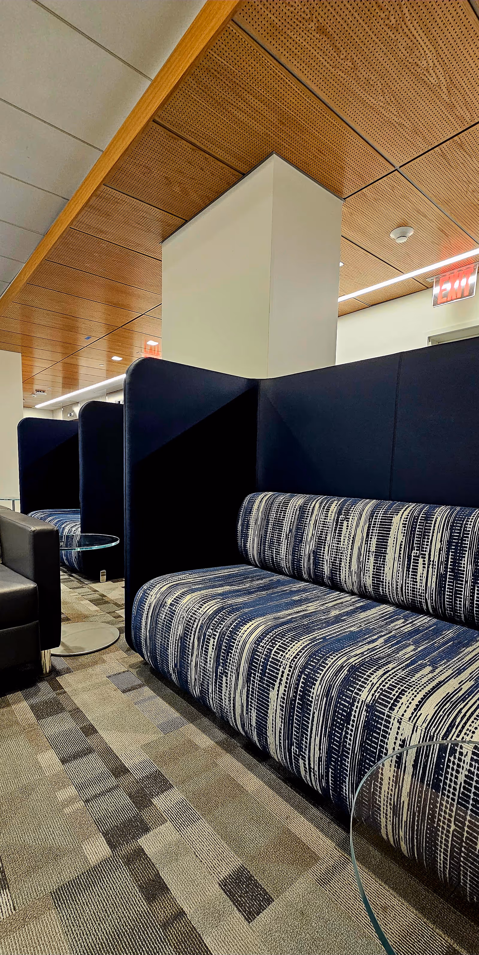 Interior lounge area with blue striped booth seating, dark partitions, and a carpeted floor.