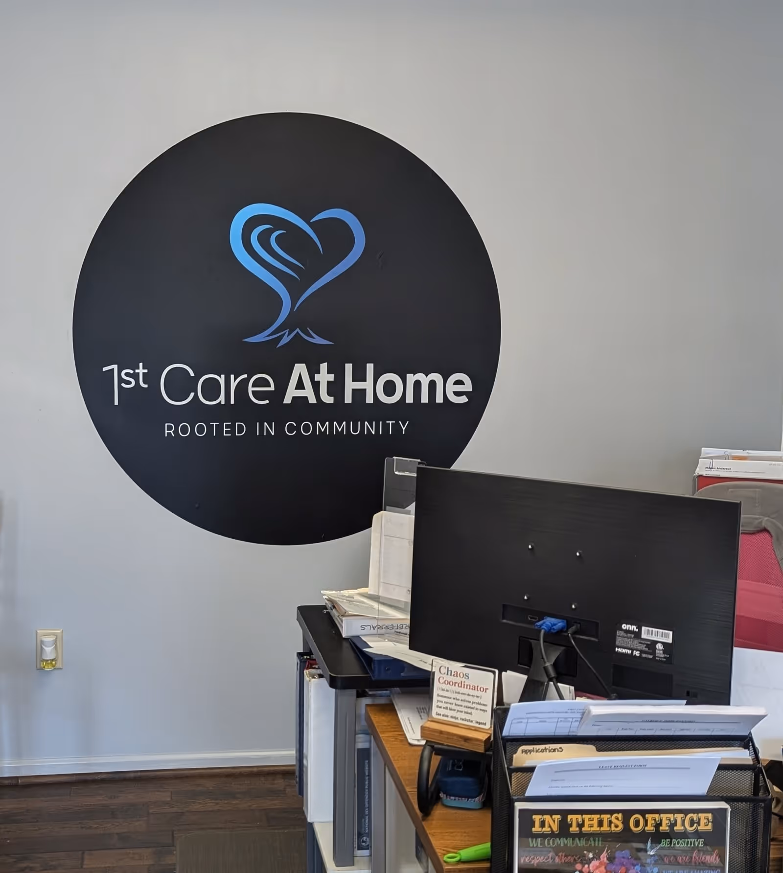 Reception area with a large circular 1st Care At Home logo on the wall.